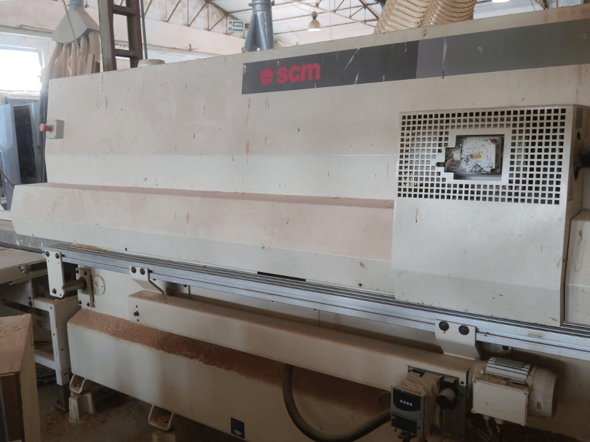 Centro di lavorazione del legno a controllo numerico SCM Windor60, vista frontale. Si notano i comandi della macchina e il sistema di aspirazione della polvere, con trucioli di legno sotto.