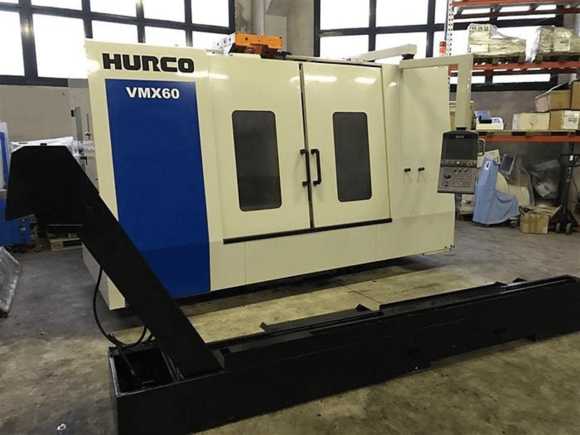 Macchina CNC HURCO VMX60 in un'officina, vista frontale, con pannello di controllo e guida di supporto nera collegata.