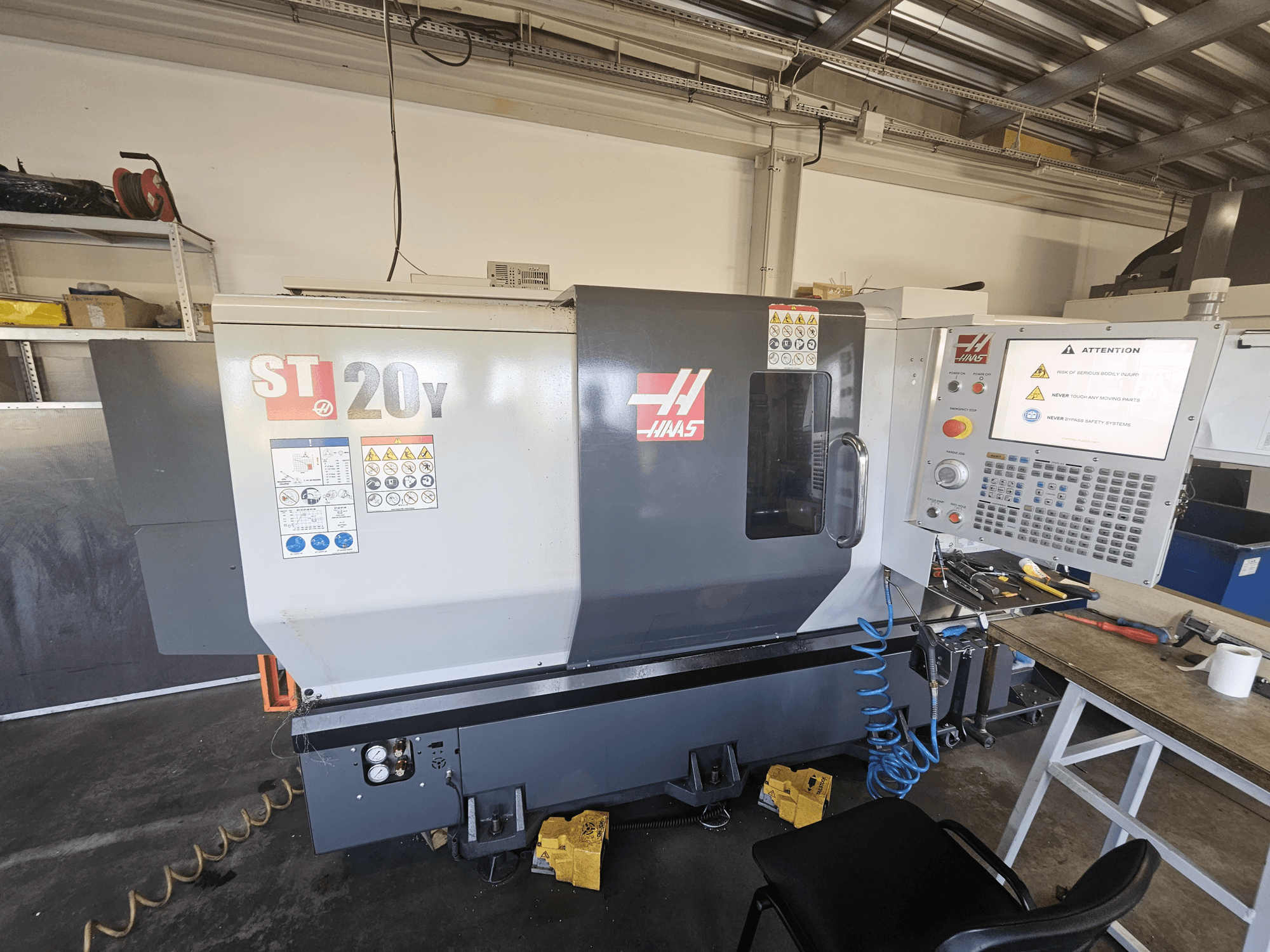 Tornio CNC Haas ST-20Y, vista frontale; include il pannello di controllo, le avvertenze di sicurezza e l'attacco per il tubo dell'aria.