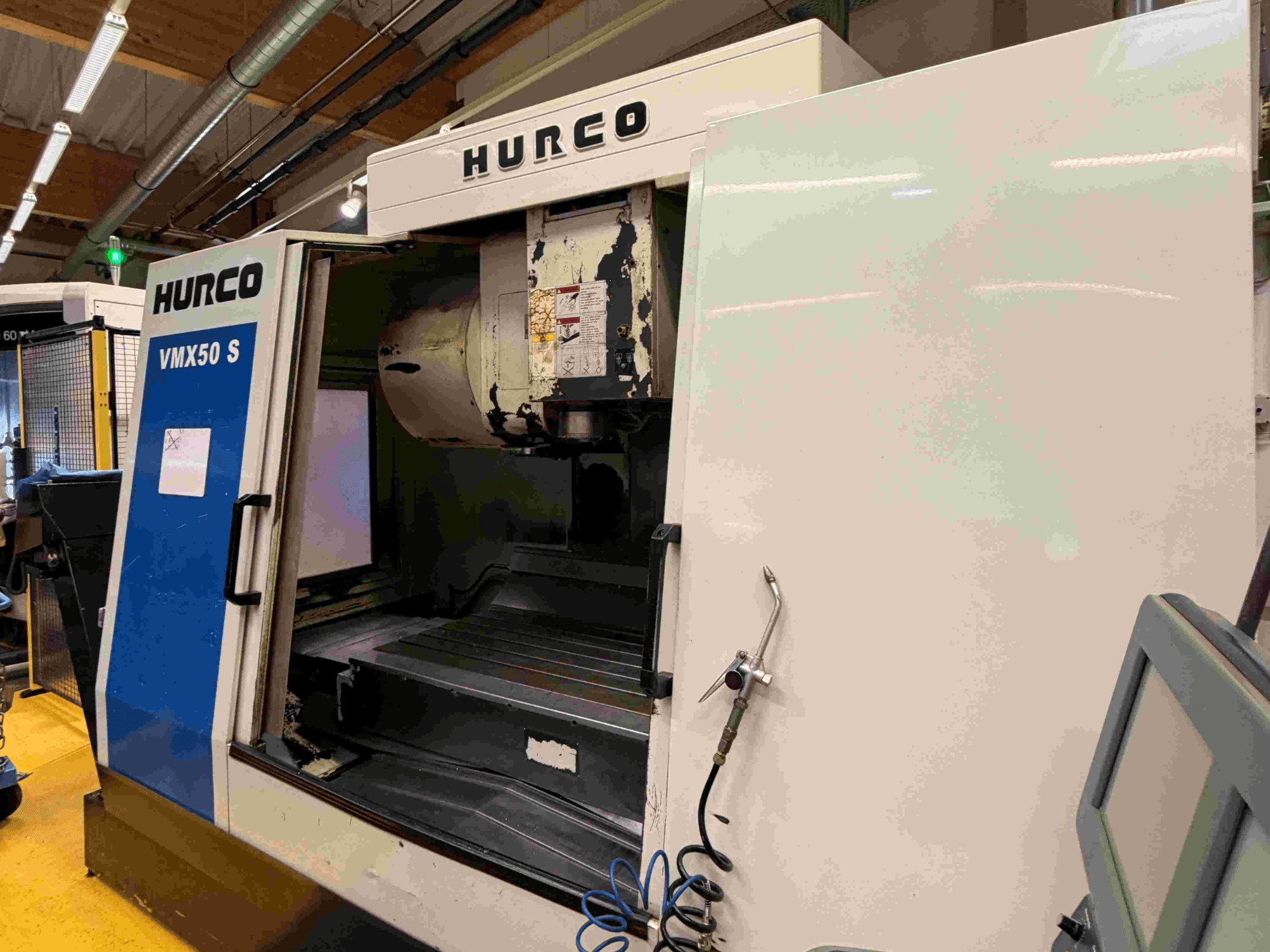 Centro di lavoro verticale Hurco VMX50 S, vista laterale, che mostra la porta aperta e il pannello di controllo.