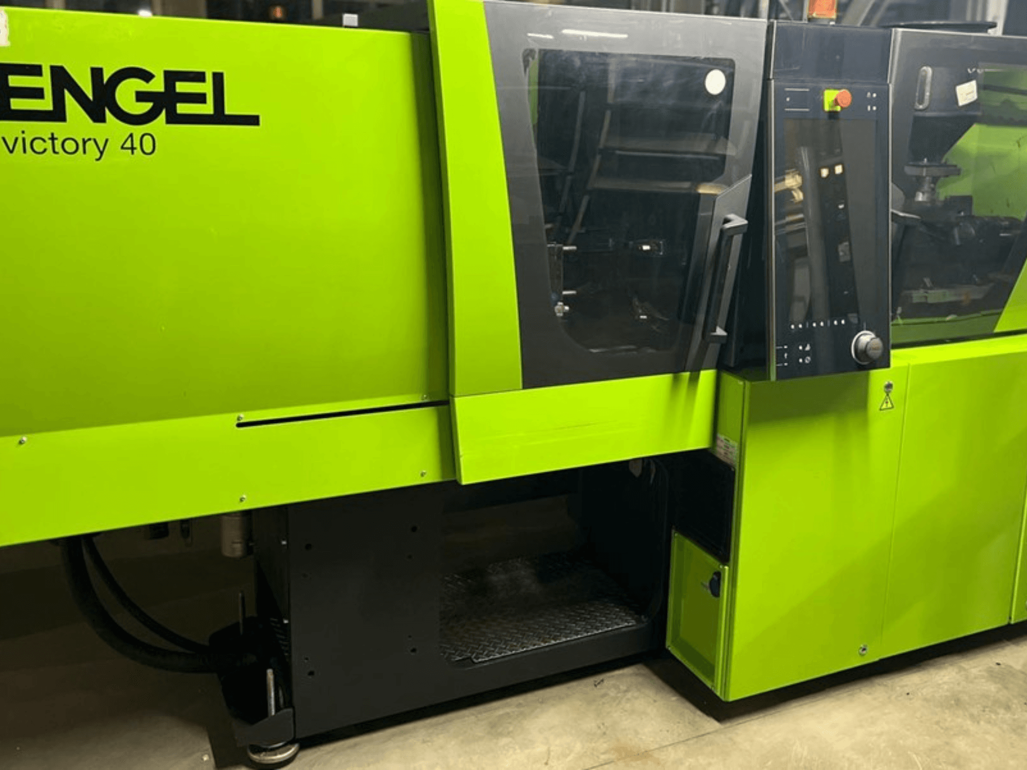 Pressa a iniezione ENGEL Victory 40 di colore verde brillante, vista frontale che mostra il pannello di controllo e lo sportello di accesso con etichetta di avvertenza.