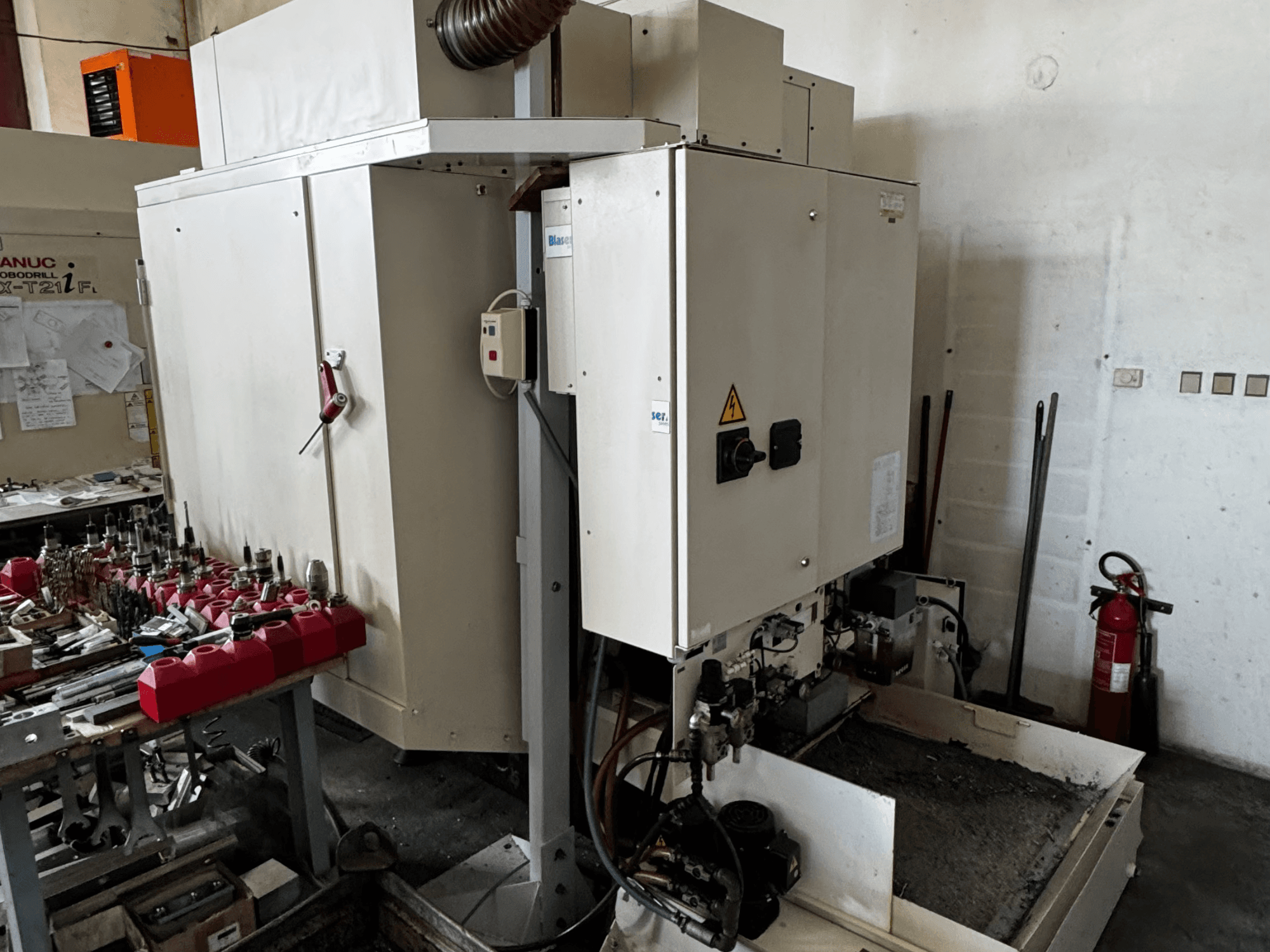 Centro di lavoro verticale FANUC Robodrill alpha-T21iFL, vista laterale che mostra il pannello di controllo, gli utensili e l'area di lavoro.