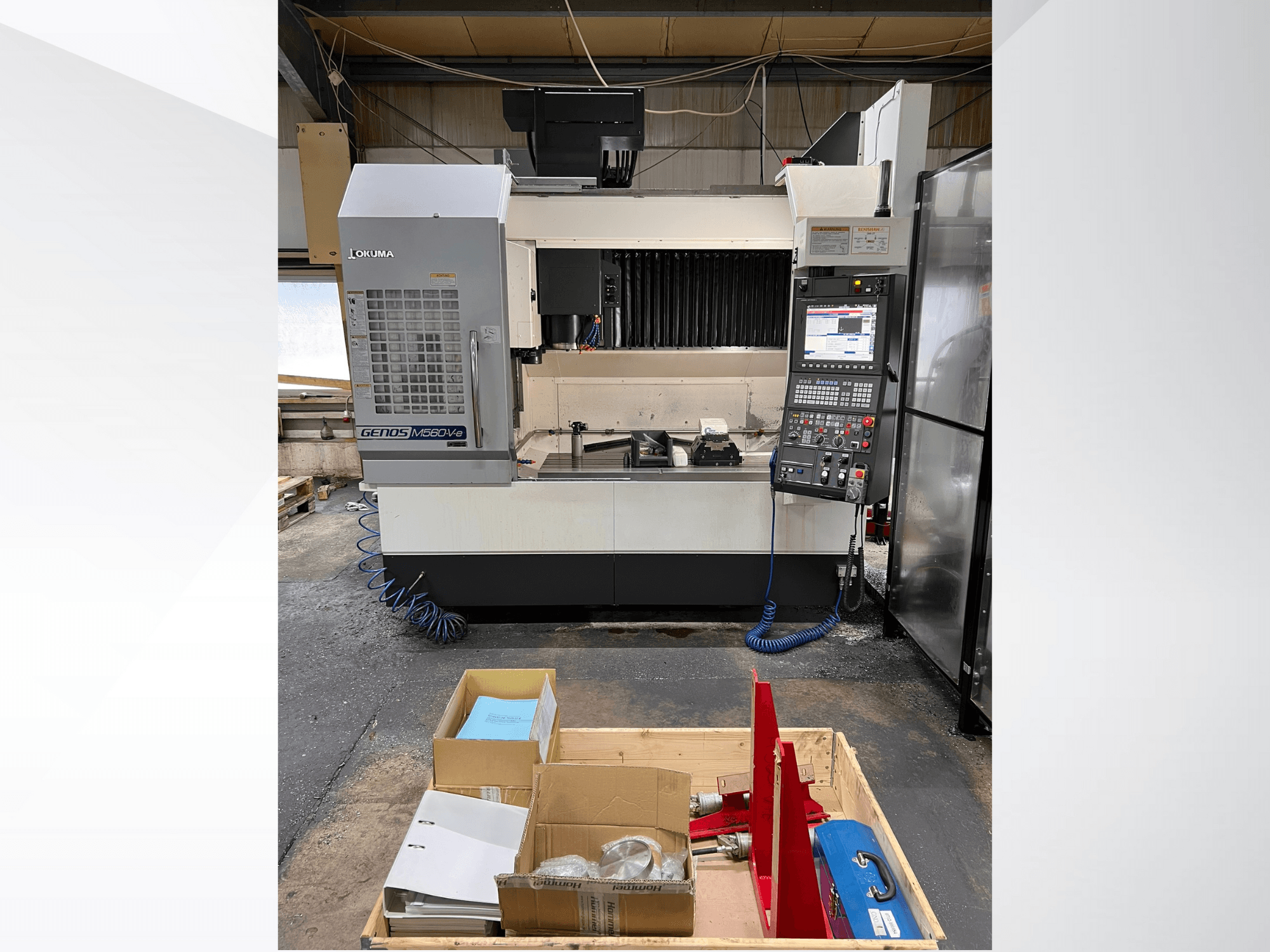 Centro di lavoro verticale Okuma GENOS M460V-5, vista frontale, con pannello di controllo visibile e utensili sul piano di lavoro.