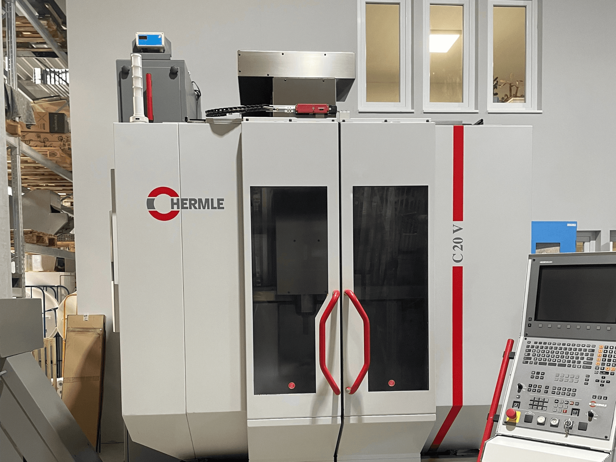 Macchina CNC Chermle C20 V, vista frontale, con pannello di controllo e maniglie rosse; design industriale con ampie porte in vetro.