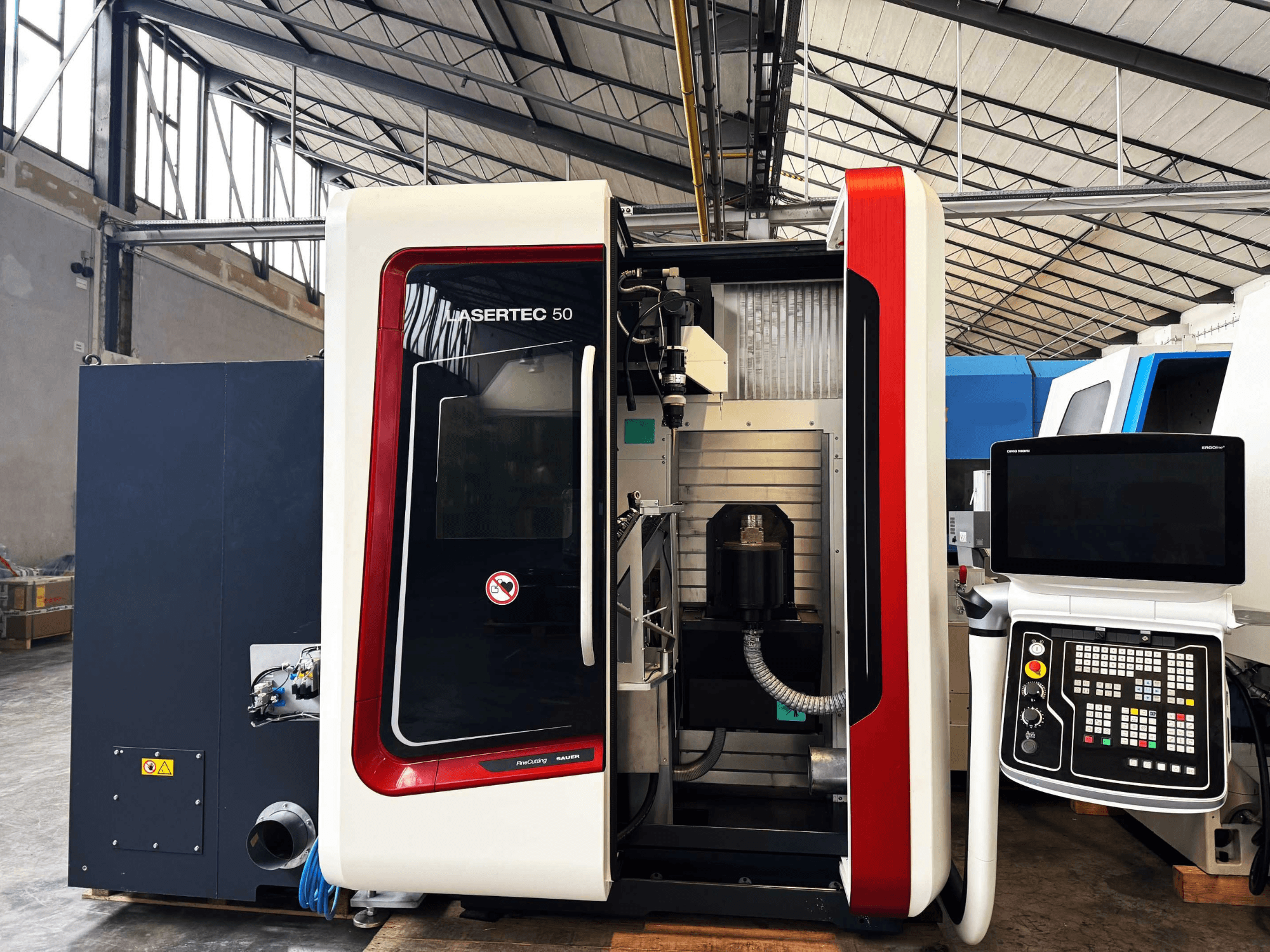 Macchina LaserTec 50 CNC in vista laterale, con pannello di controllo in bianco e nero, portautensili a vista e ambientazione industriale.
