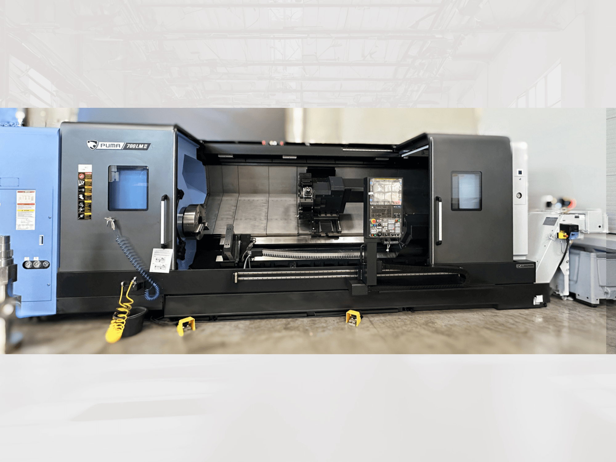 DN SOLUTIONS Centro di tornitura PUMA 700LM, vista frontale, con pannello di controllo e area di lavorazione con utensili visibili.