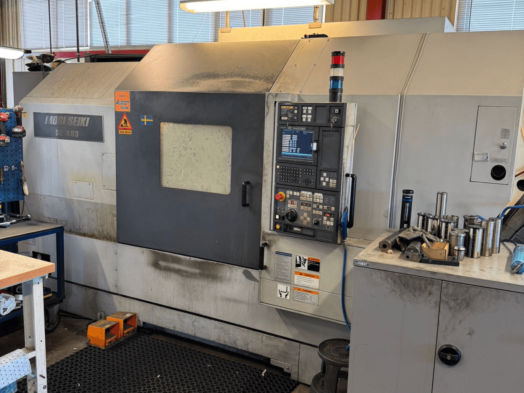 Tornio orizzontale MORI SEIKI SL-403BMC/800 in un'officina, con pannello di controllo e utensili vicini, vista laterale.