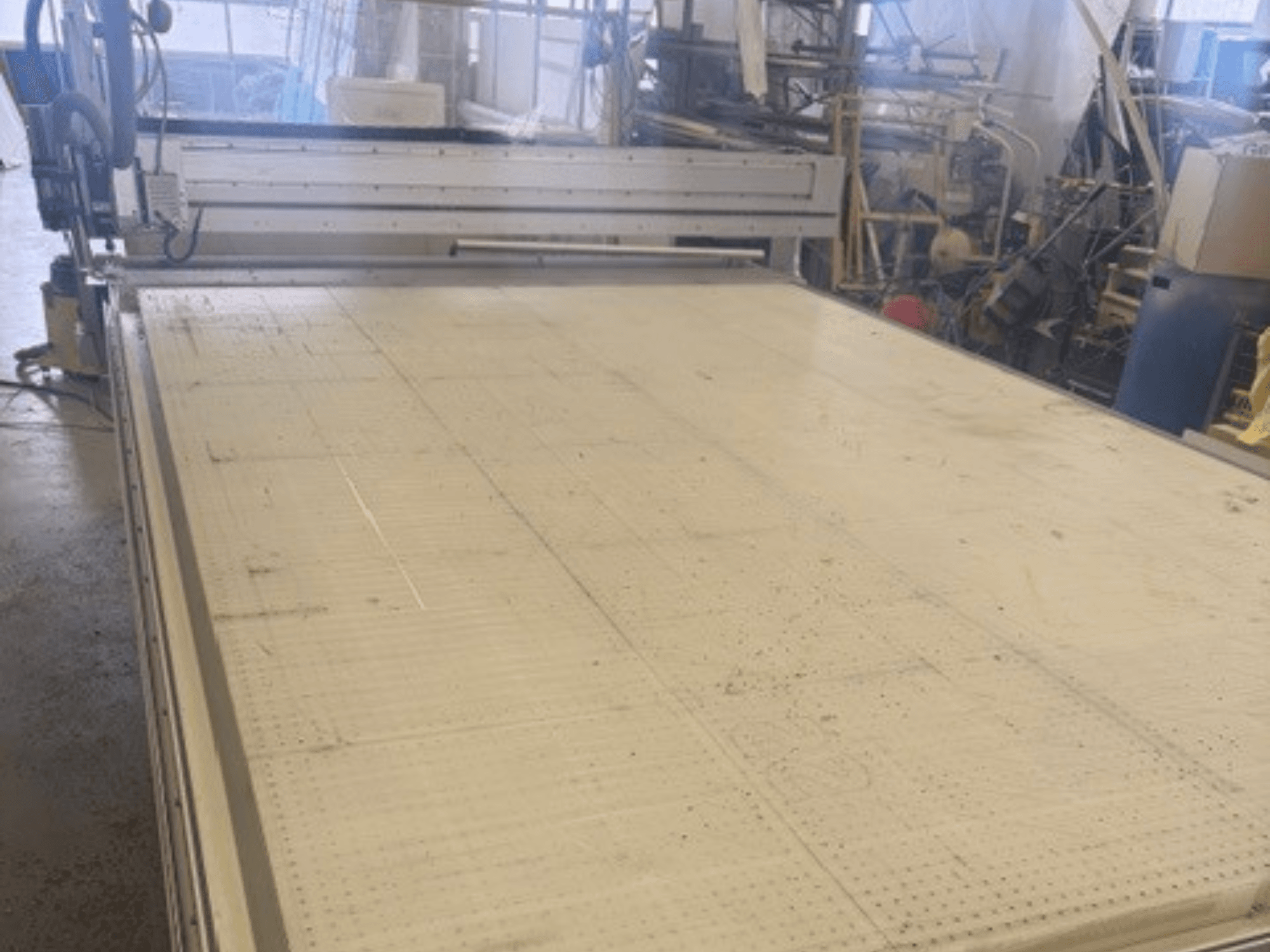 Macchina da taglio di grandi dimensioni con superficie piana, che mostra il telaio e la guida; vista da un'angolazione in un'officina.