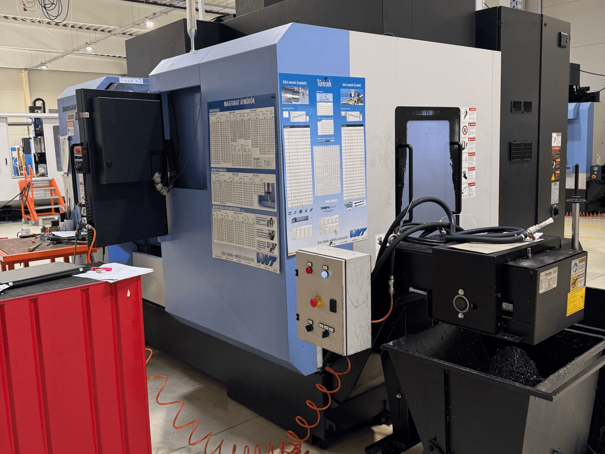 Centro di fresatura e tornitura DOOSAN DNM350/5AX, vista laterale che mostra il pannello di controllo e il serbatoio del liquido di raffreddamento, con dettagli operativi visibili.