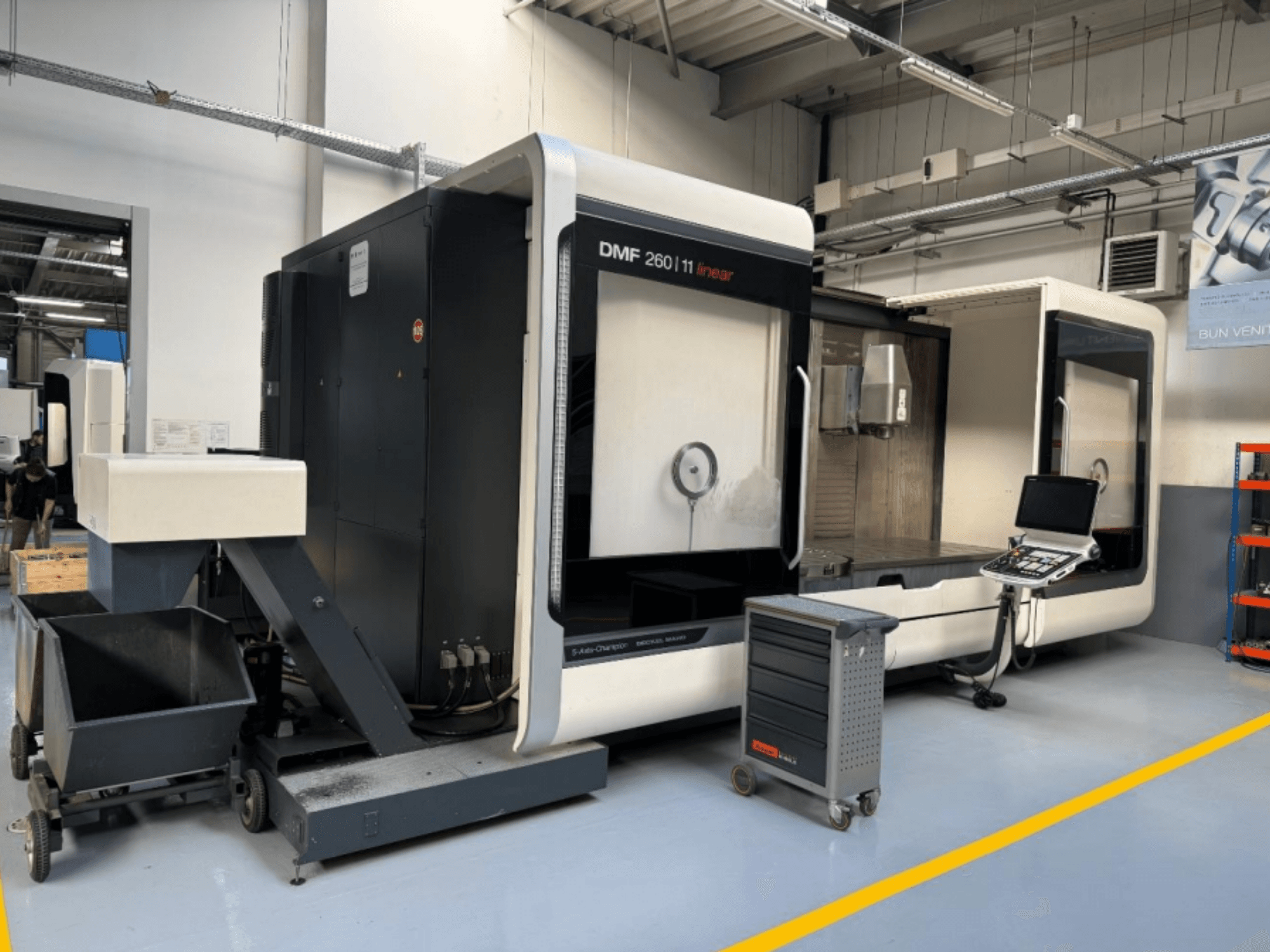 La fresatrice lineare DMG MORI DMF 260 vista frontalmente, con il pannello di controllo degli utensili e il carrello portautensili mobile nelle vicinanze.
