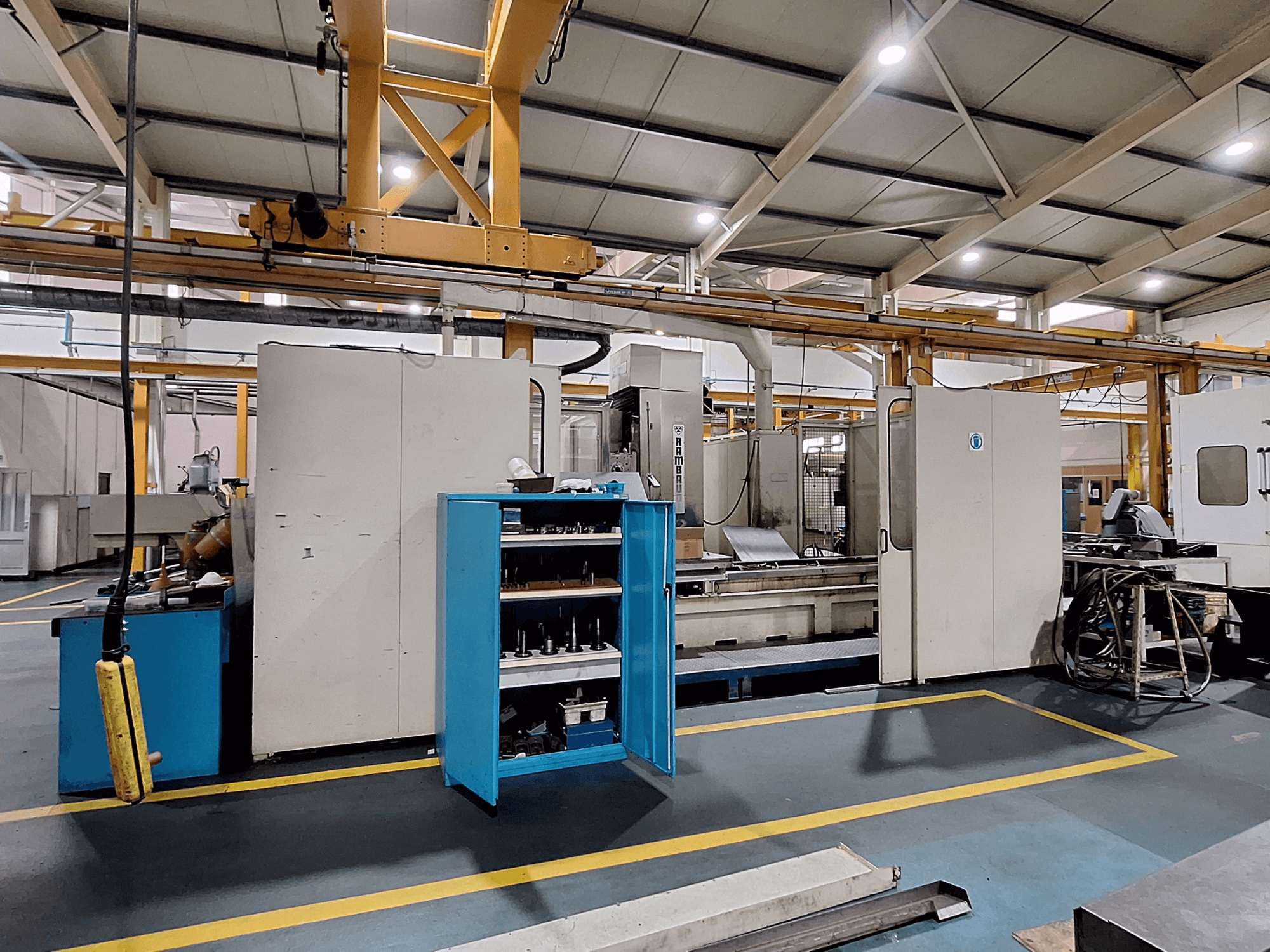 Fresatrice a portale Rambaudi RX 1250, vista frontale con magazzino utensili, in un ampio spazio di lavoro industriale.