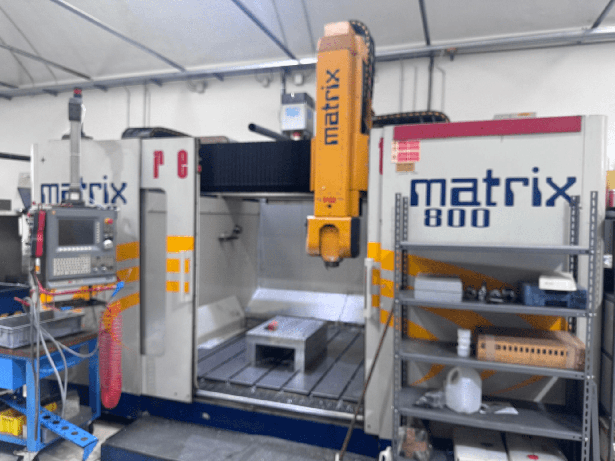 Macchina CNC Matrix 800 vista in officina, con pannello di controllo, utensili e tavolo di lavoro con vari oggetti.