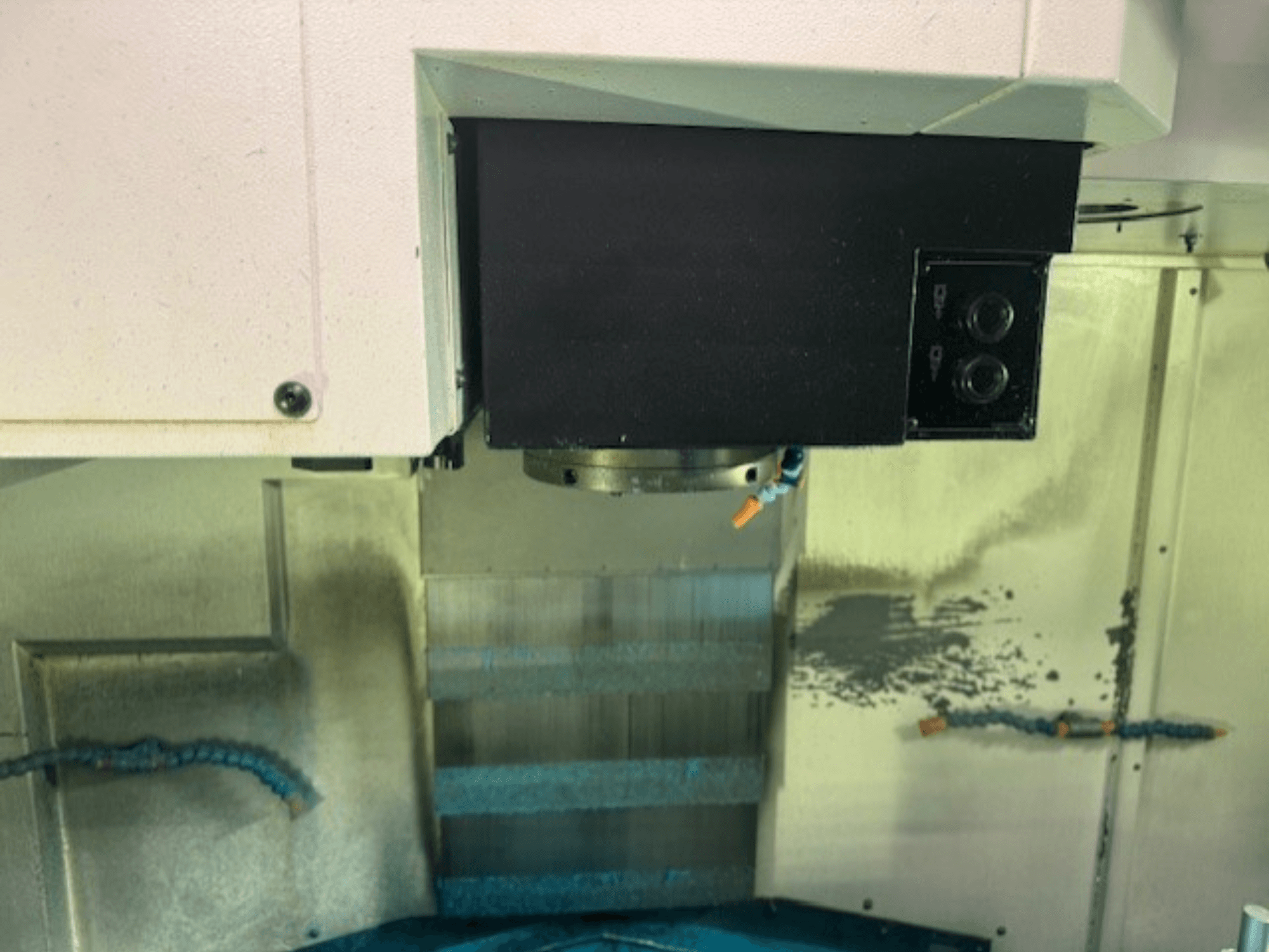 Primo piano del pannello di controllo di una fresatrice CNC e del portautensili, con i dettagli del marchio, i pulsanti e la superficie di lavoro.