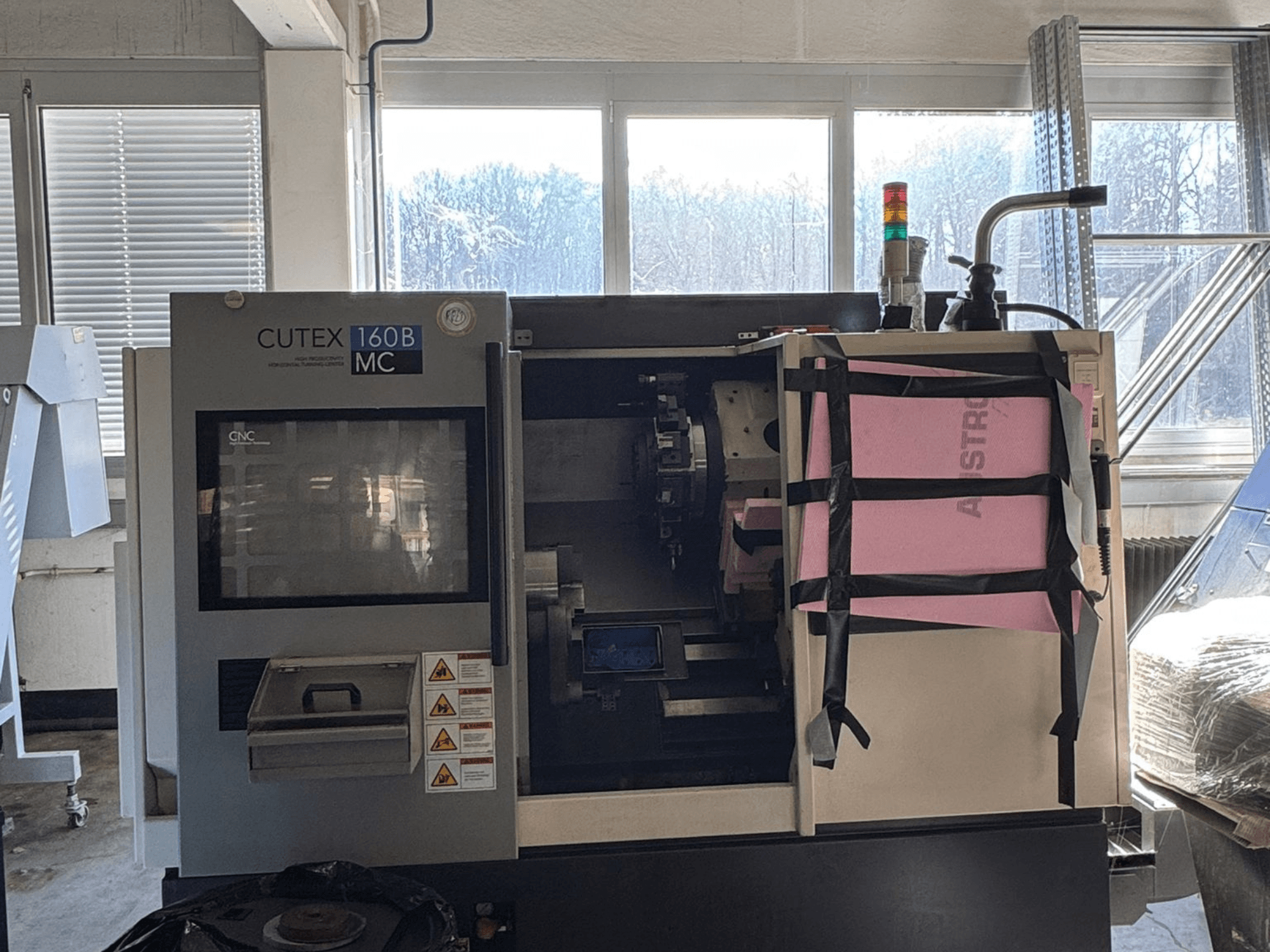 Vista frontale del tornio orizzontale HWACHEON CUTEX 160 B VDI con pannello di comando e serbatoio del liquido di raffreddamento, dotato di una luce di sicurezza.