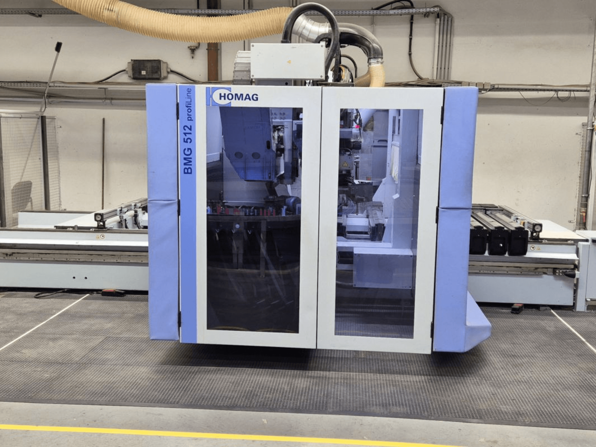 Macchina CNC HOMAG BMG 512 ProfiLine, vista frontale, con pannello in vetro, utensili di precisione visibili e ambientazione industriale.