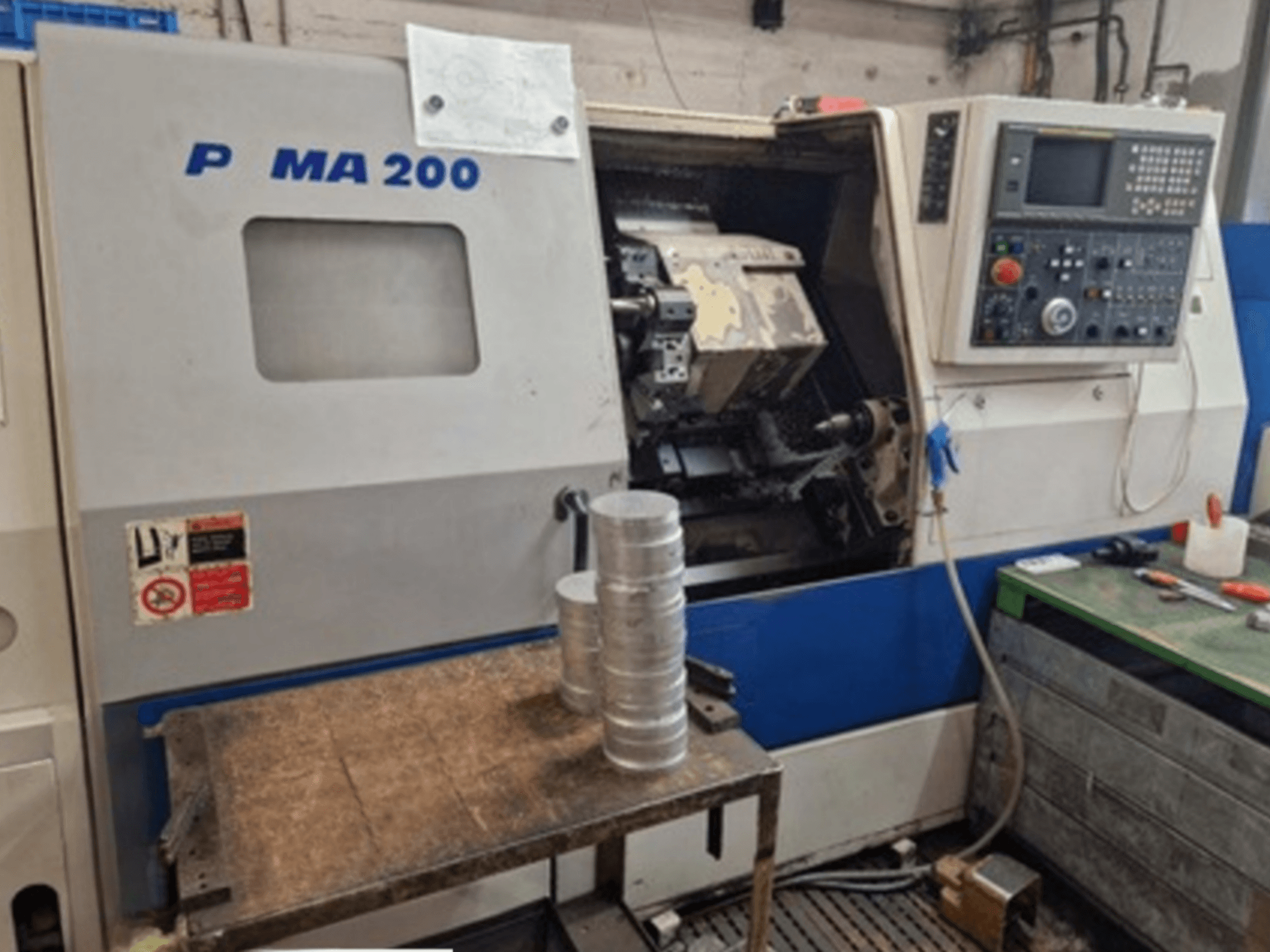 Tornio orizzontale DAEWOO EcoTurn 200, vista frontale, con pezzi di alluminio su una tavola, pannello di controllo visibile.