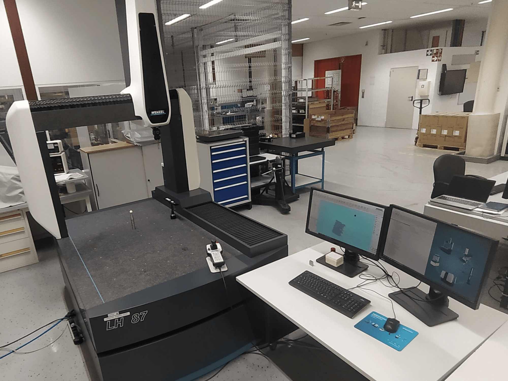 Macchina di misura a coordinate Wenzel LH 87 visibile in un laboratorio, con doppio monitor e sonda di misura sul tavolo.
