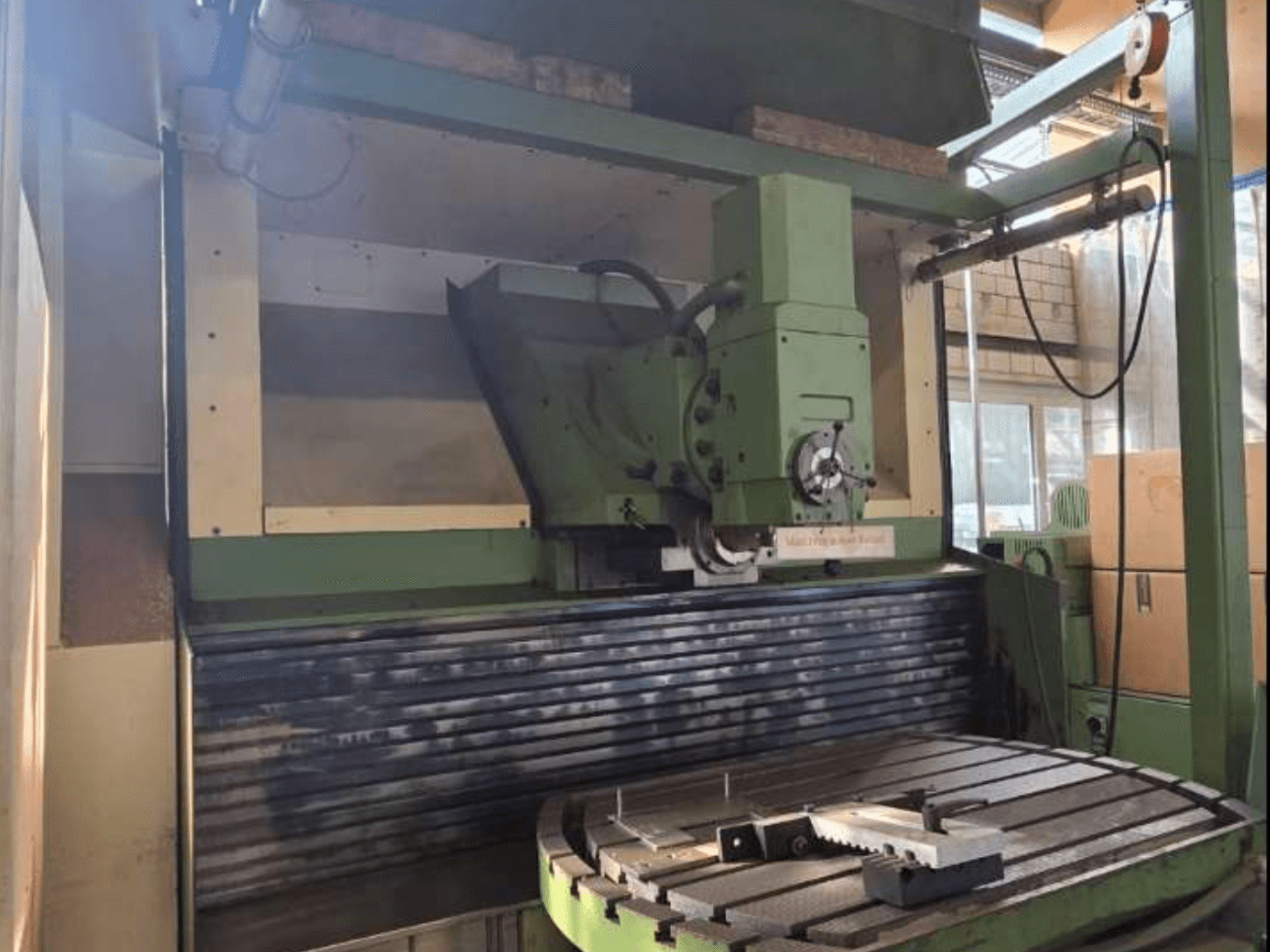 Centro di lavoro universale MAHO MH1000 C in vista frontale, con struttura verde, mandrino e tavola rotante con un pezzo.