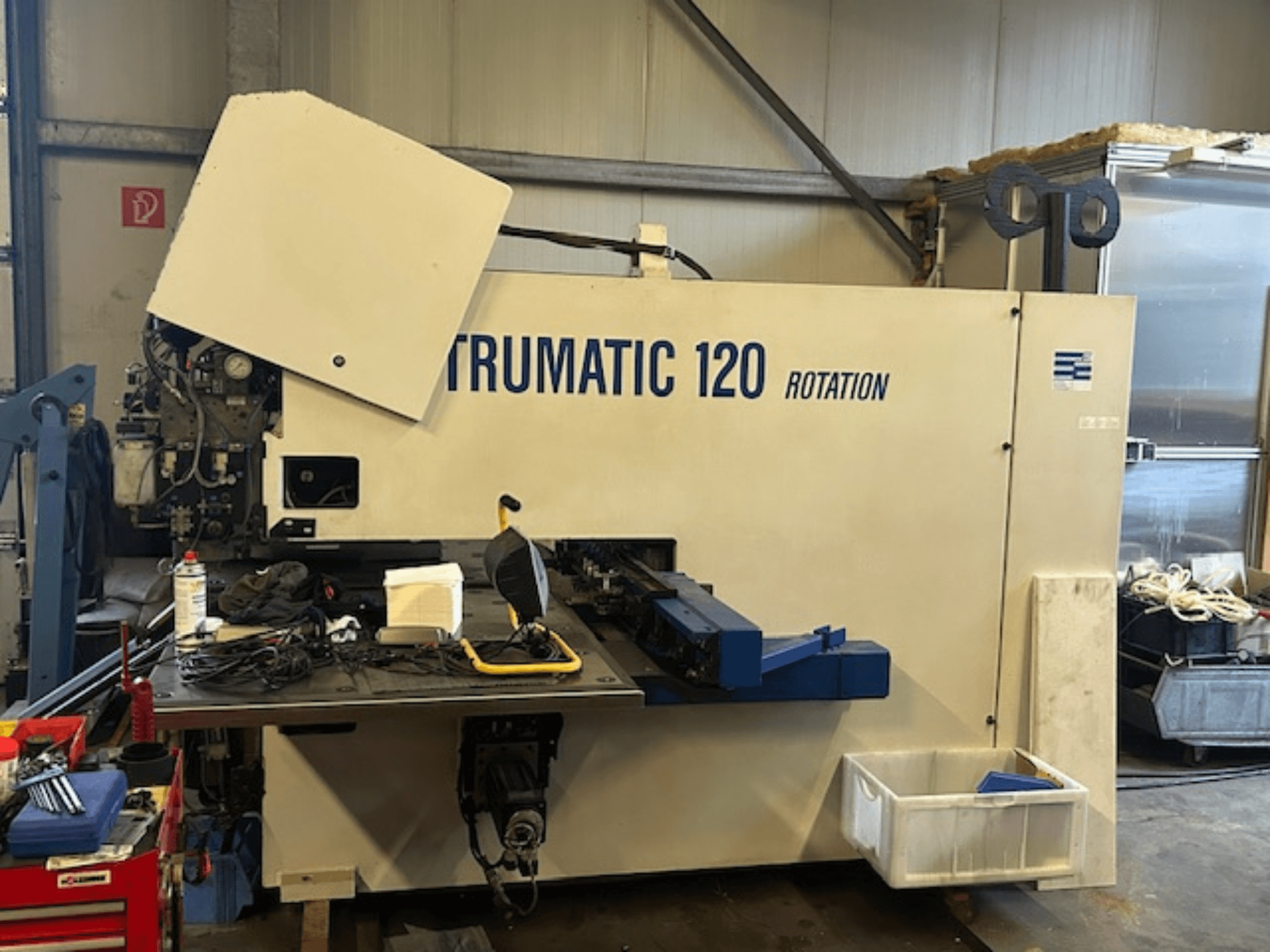 Punzonatrice CNC TRUMPF Trumatic 120R in un'officina, vista frontale che mostra il pannello di controllo e gli utensili sul tavolo.