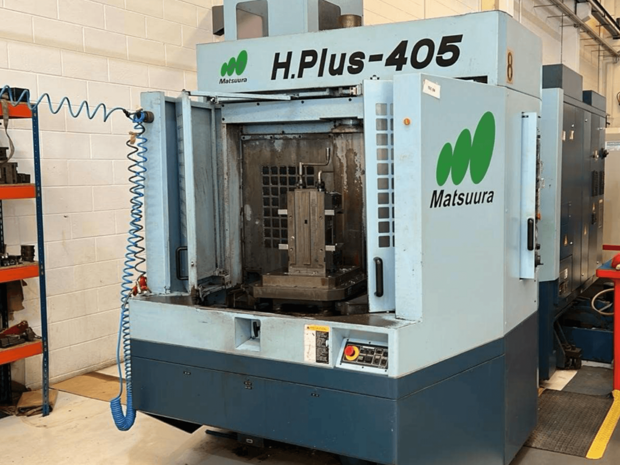 Vista frontale di un centro di lavorazione orizzontale Matsuura H.Plus 405 con lo sportello aperto, che mostra l'area di lavoro e il pannello di controllo.