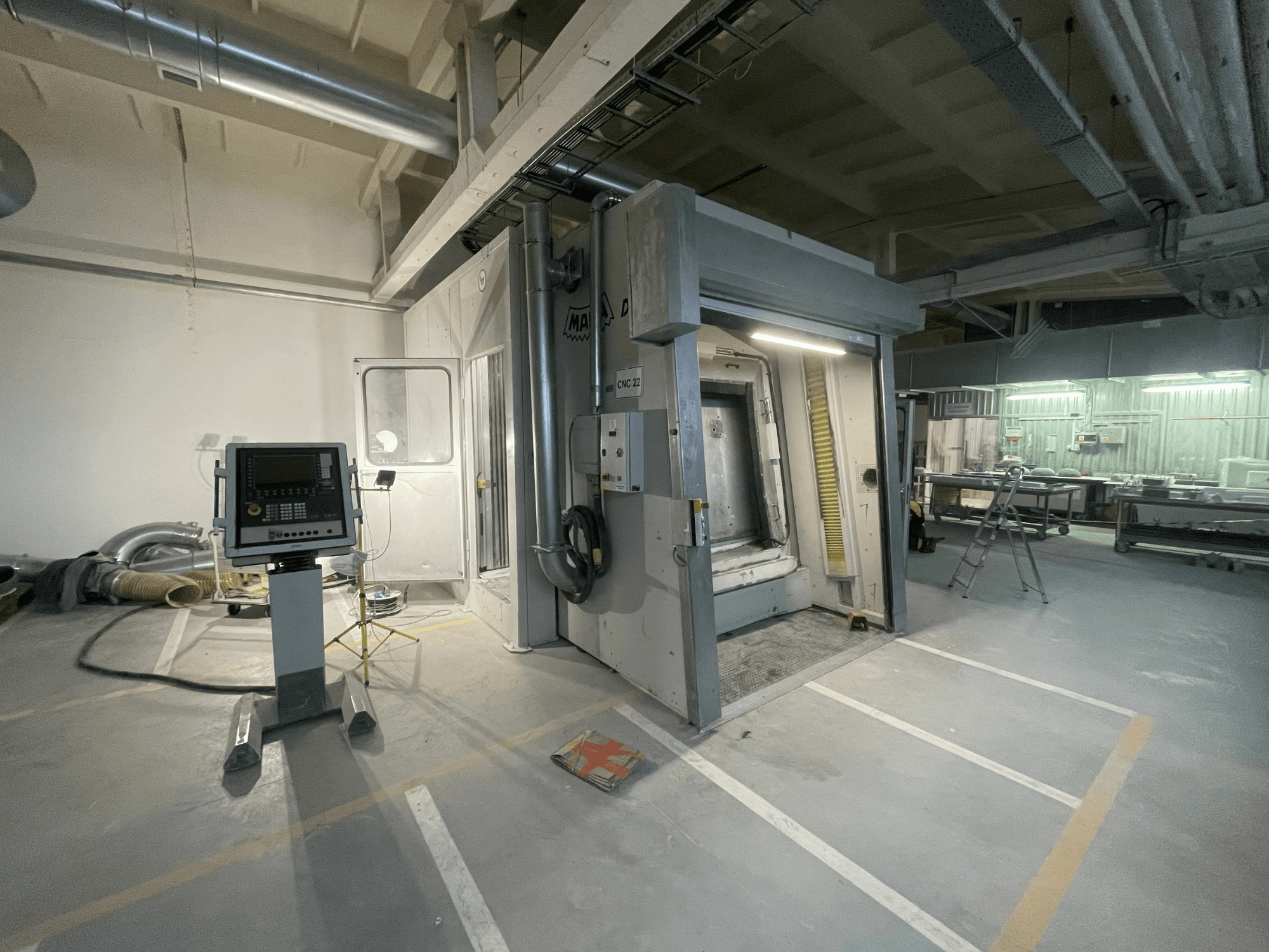 Centro di lavoro verticale MAKA DC 3 in un'officina, visto dal davanti, con pannello di controllo e porta aperta.