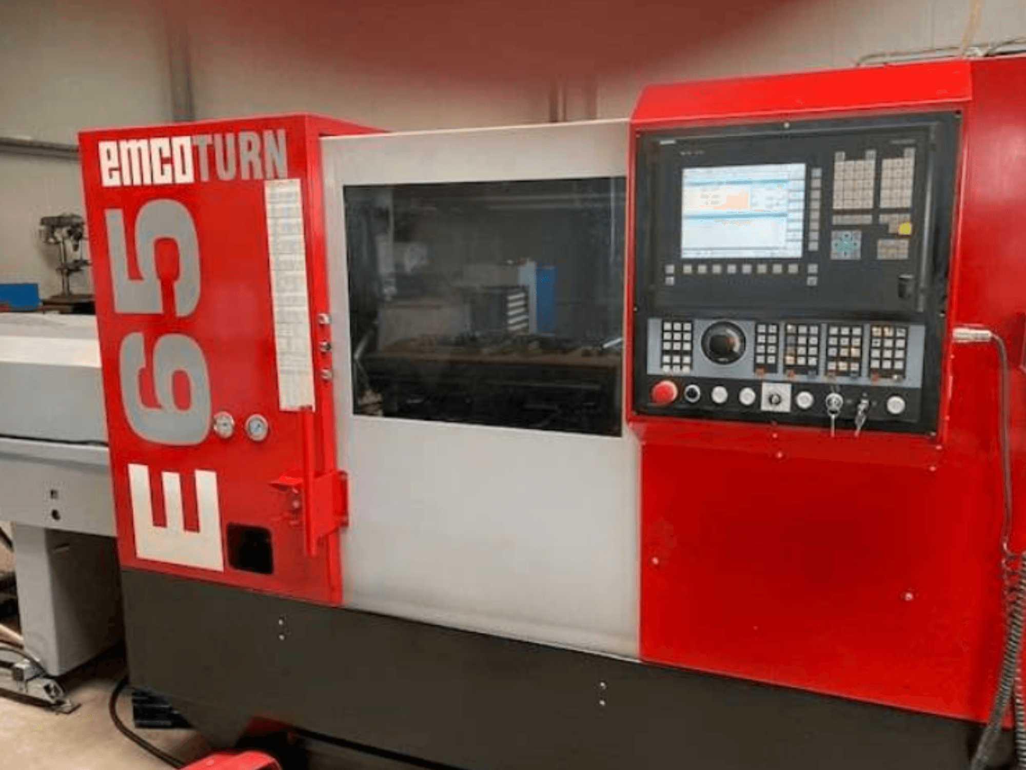 Tornio CNC EMCO Turn E65, vista frontale che mostra il pannello di controllo, l'ampio display e l'area di lavoro dietro il vetro.