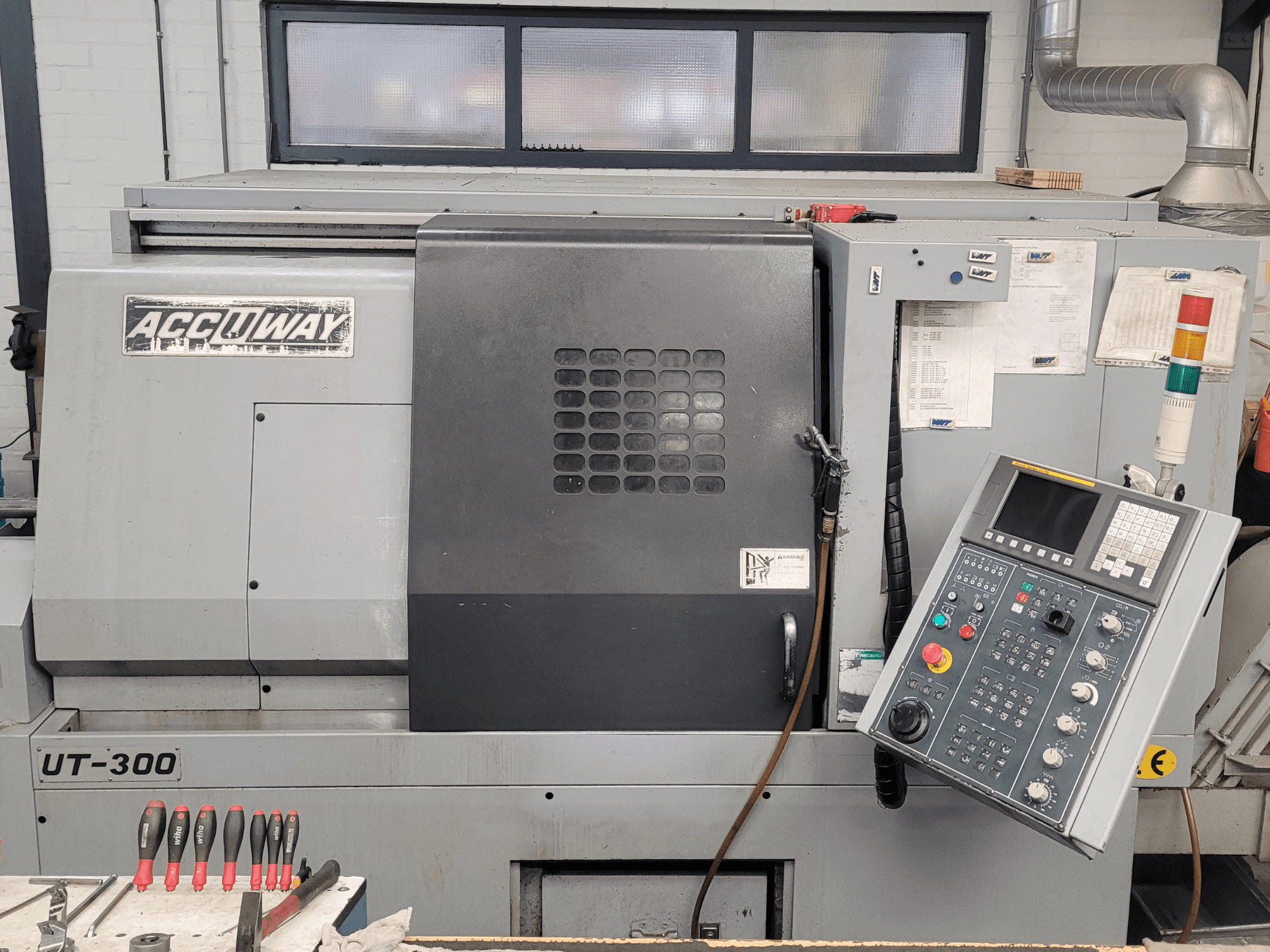 Macchina CNC Accuway UT-300 in vista frontale, con pannello di controllo e vari pulsanti operativi, in un'officina.