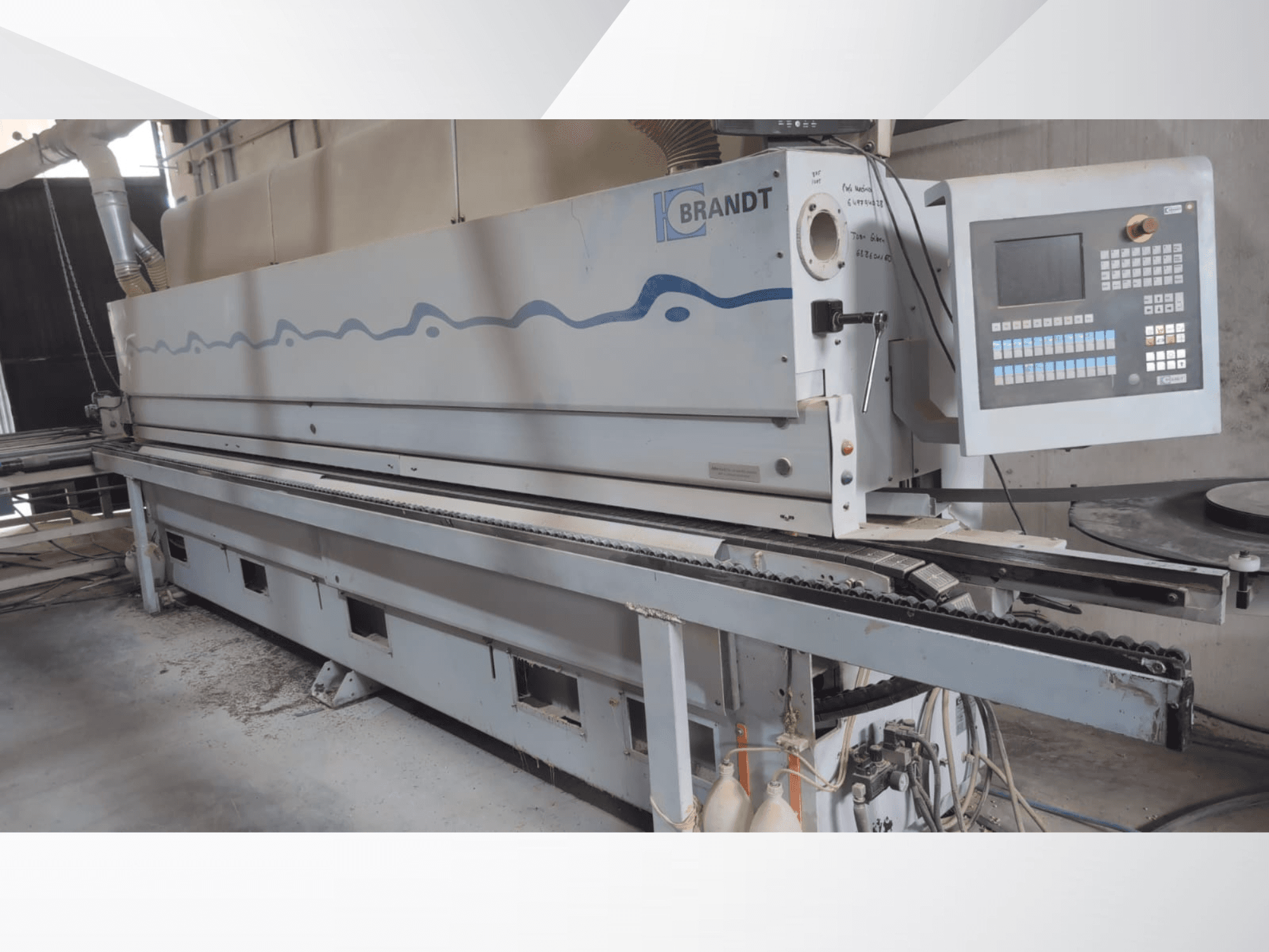 Bordatrice BRANDT KDF 560 vista frontale, con pannello di controllo e nastro trasportatore di alimentazione, con residui di polvere visibili sul pavimento.