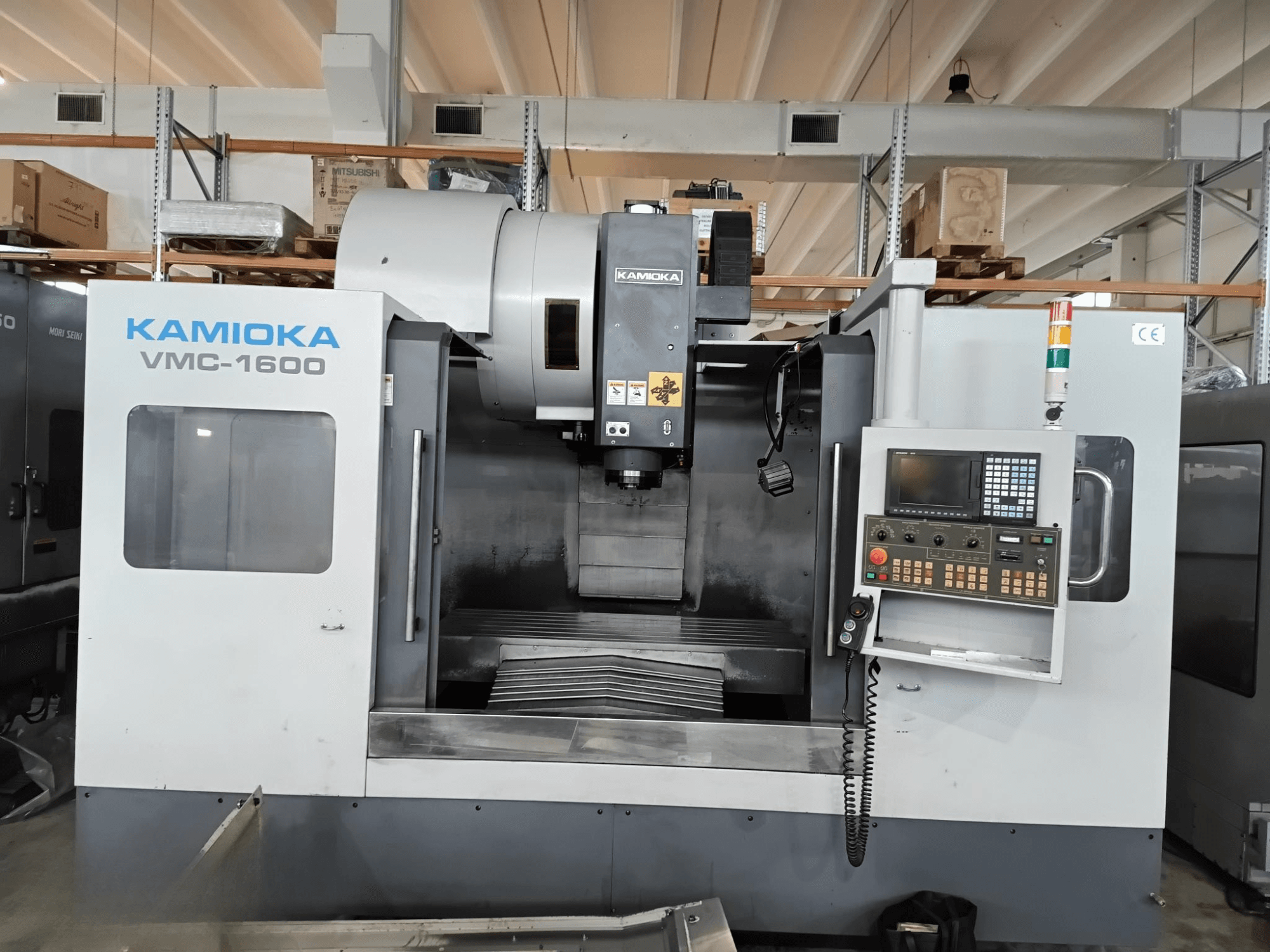 Centro di lavoro verticale Kamioka VMC-1600 in un ambiente industriale, vista frontale con pannello di controllo e piano di lavoro visibile.