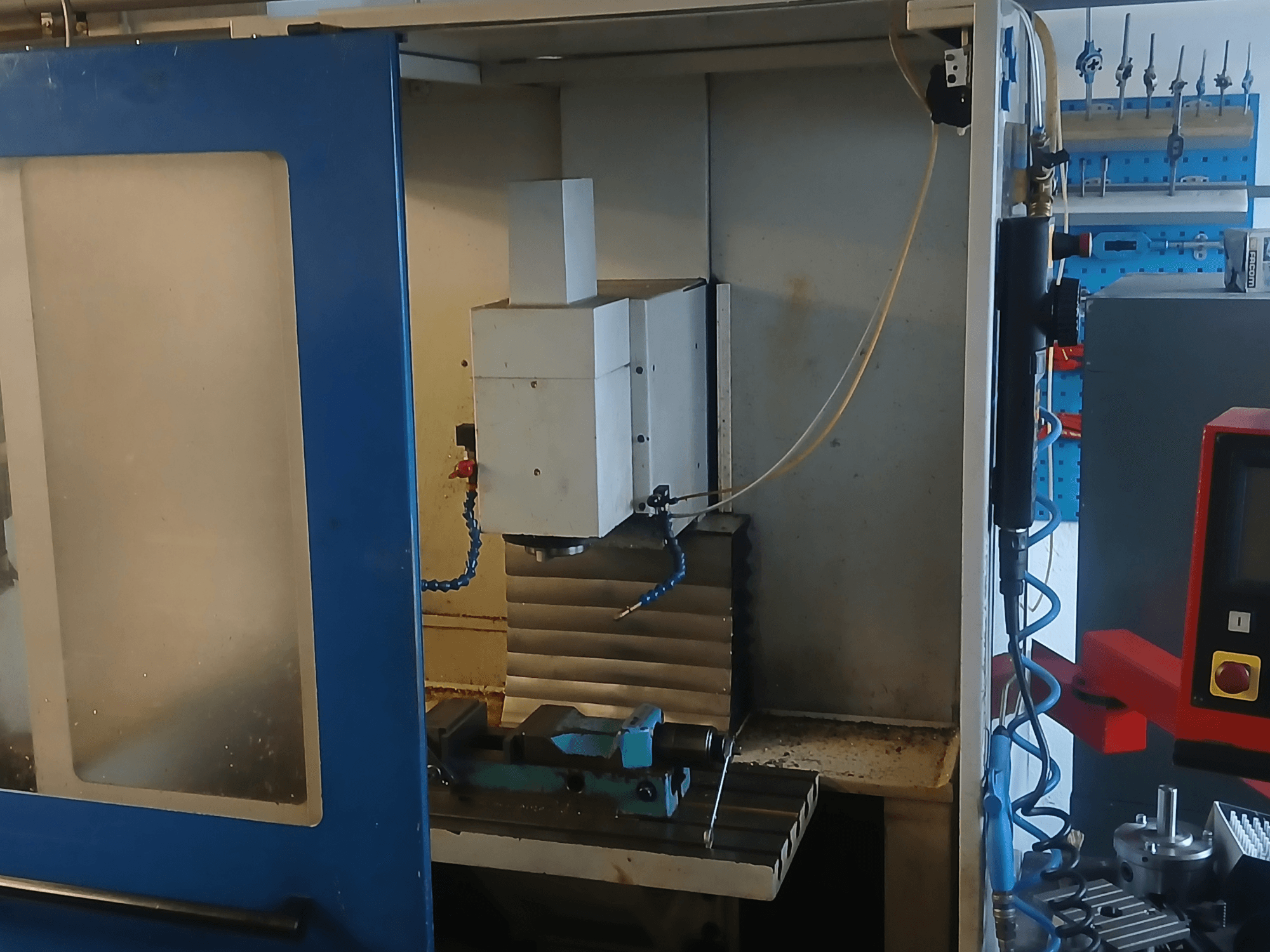 Centro di lavorazione verticale MACMON M 454 V visto frontalmente, con in primo piano il mandrino e l'area di lavorazione, con gli utensili nelle vicinanze.