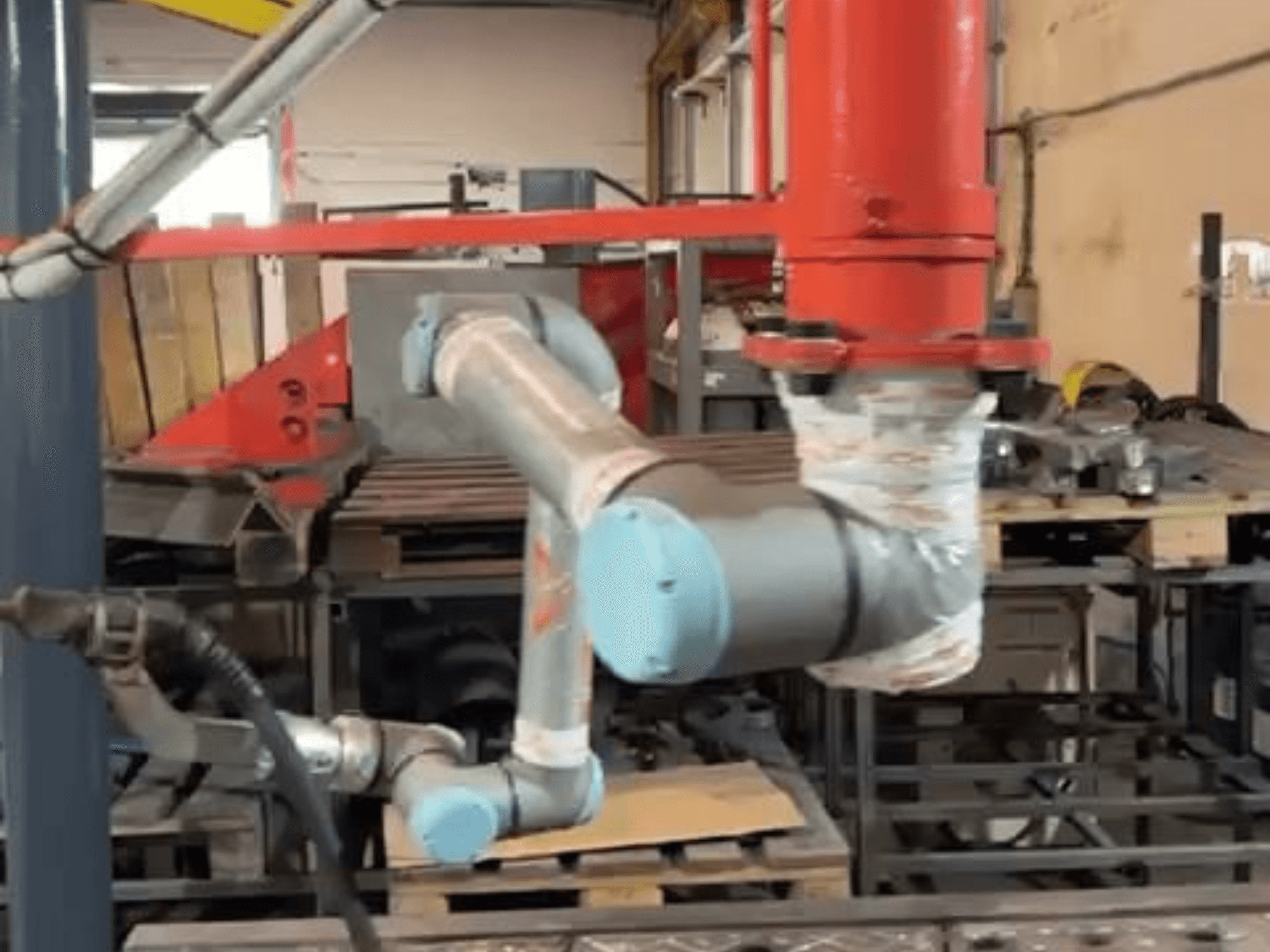 Robot collaborativo UR10e di Universal Robots in un'officina; vista laterale che mostra i movimenti del braccio e delle articolazioni in prossimità dei macchinari.