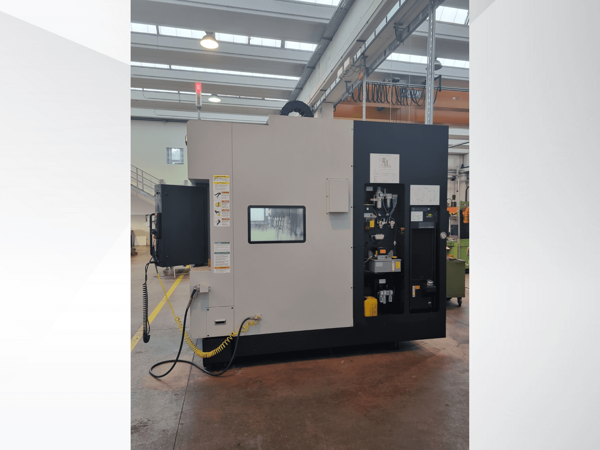 Macchina industriale vista di lato, dotata di un pannello di controllo con pulsanti, indicatori ed etichetta di sicurezza.