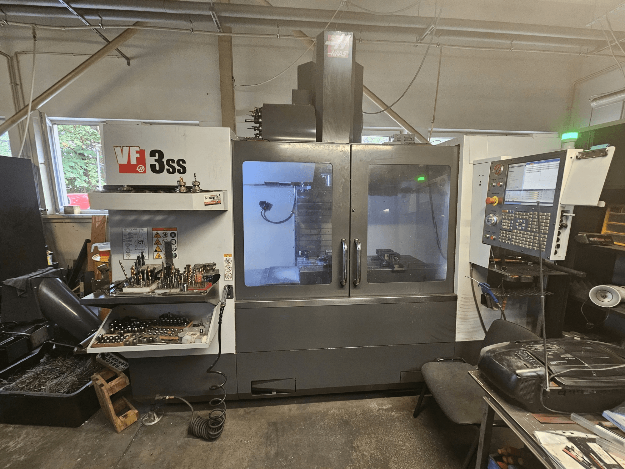 Centro di lavorazione verticale Haas VF-3SS in un'officina, vista frontale che mostra il pannello di controllo e il vano porta-utensili.