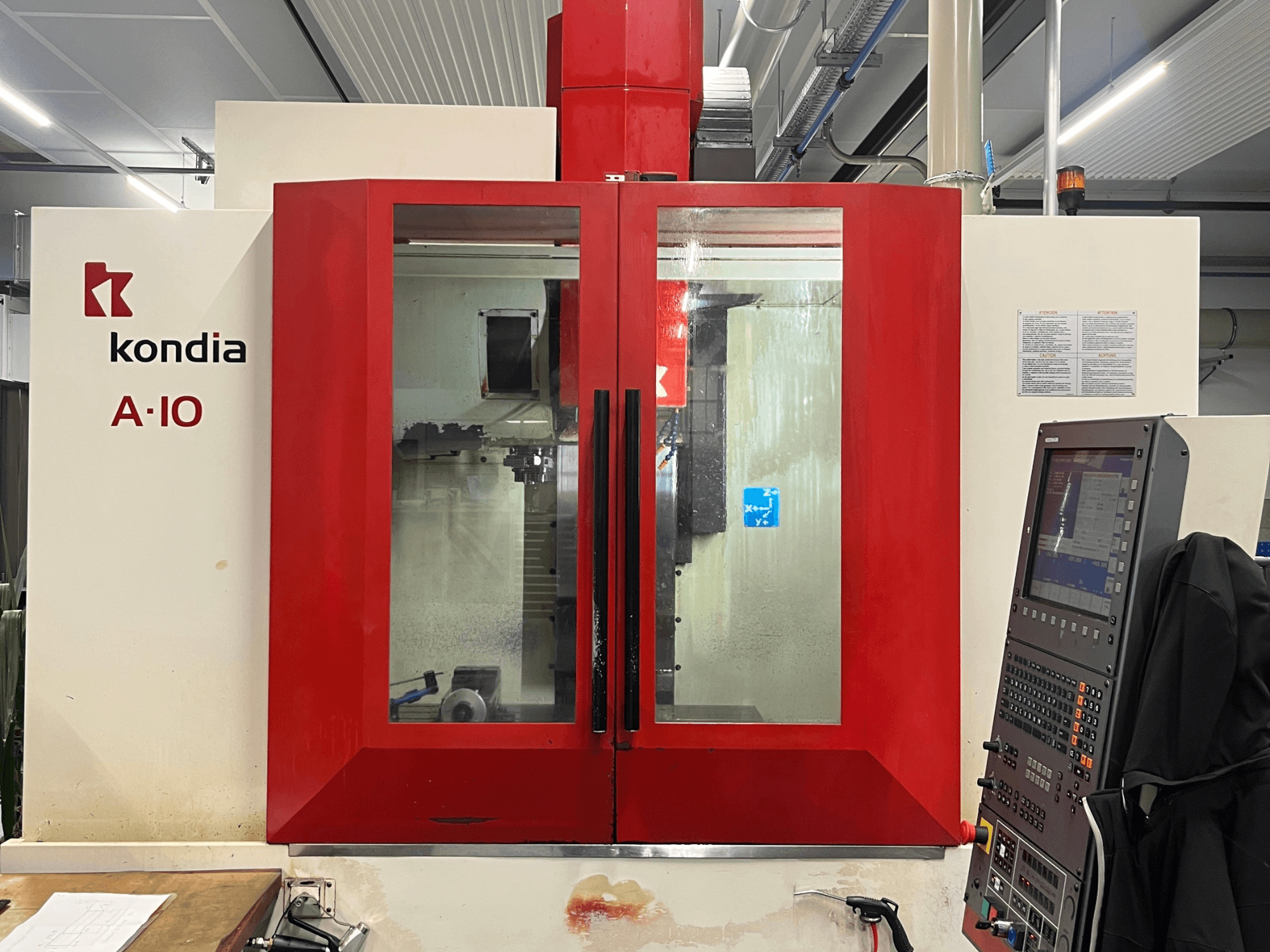 Centro di lavoro verticale KONDIA A10, vista frontale; presenta porte in vetro rosso e pannello di controllo sulla destra.