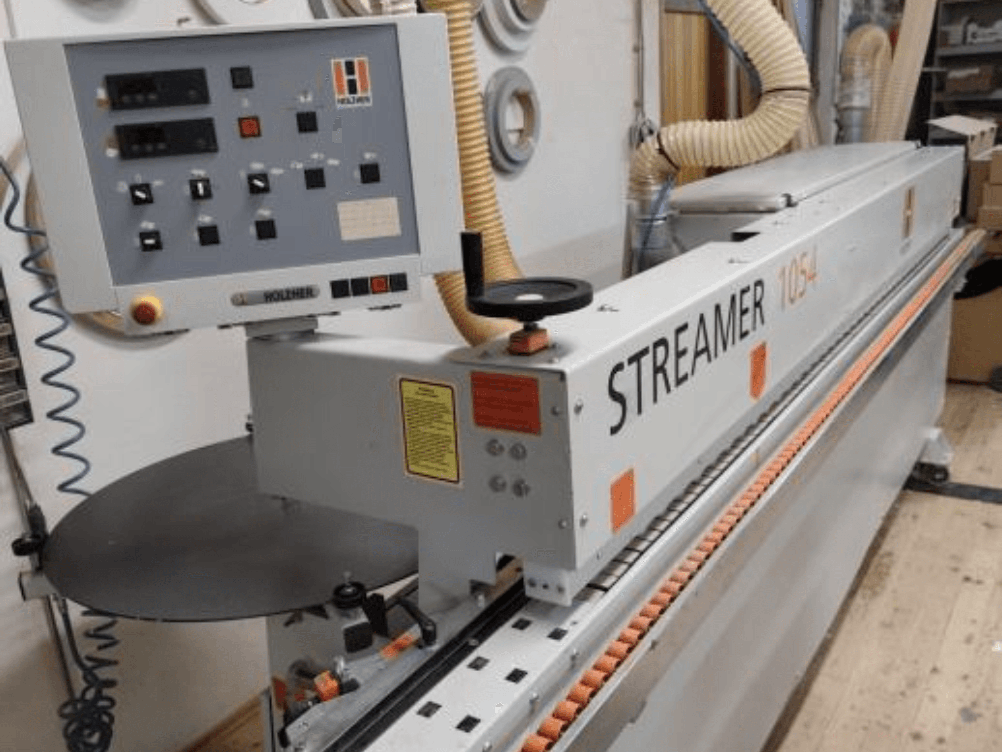Bordatrice HOLZHER Streamer 1054, vista laterale che mostra il pannello di controllo e il sistema di alimentazione su uno sfondo da officina.