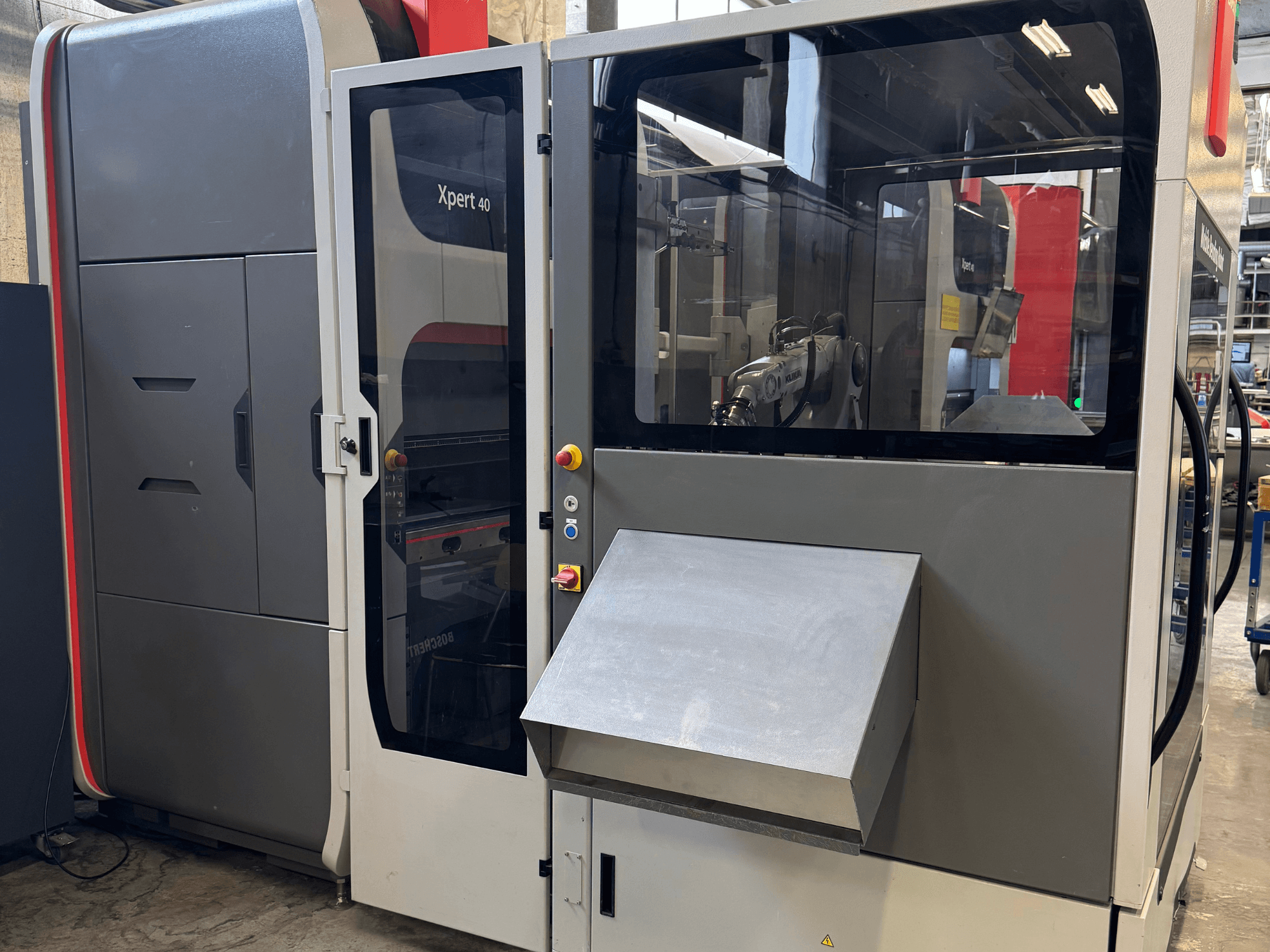 La pressa piegatrice Bystronic Xpert 40/1030 in vista frontale, che mostra il pannello di controllo, il contenitore in vetro e le caratteristiche di design pulito.