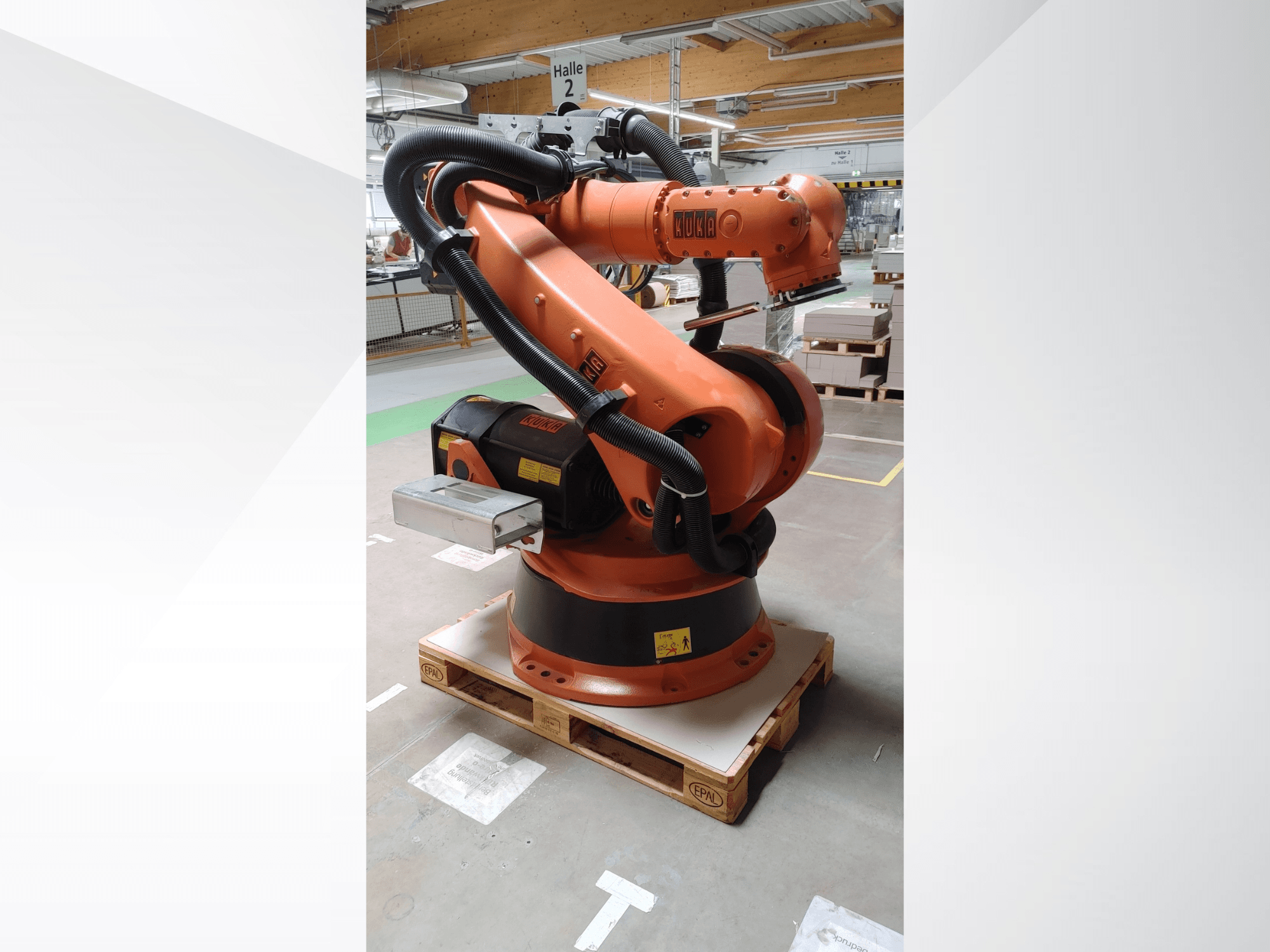 Braccio robotico KUKA KR140-3 COMP di colore arancione, vista frontale su un pallet di legno, con braccio curvo e scatola di controllo.