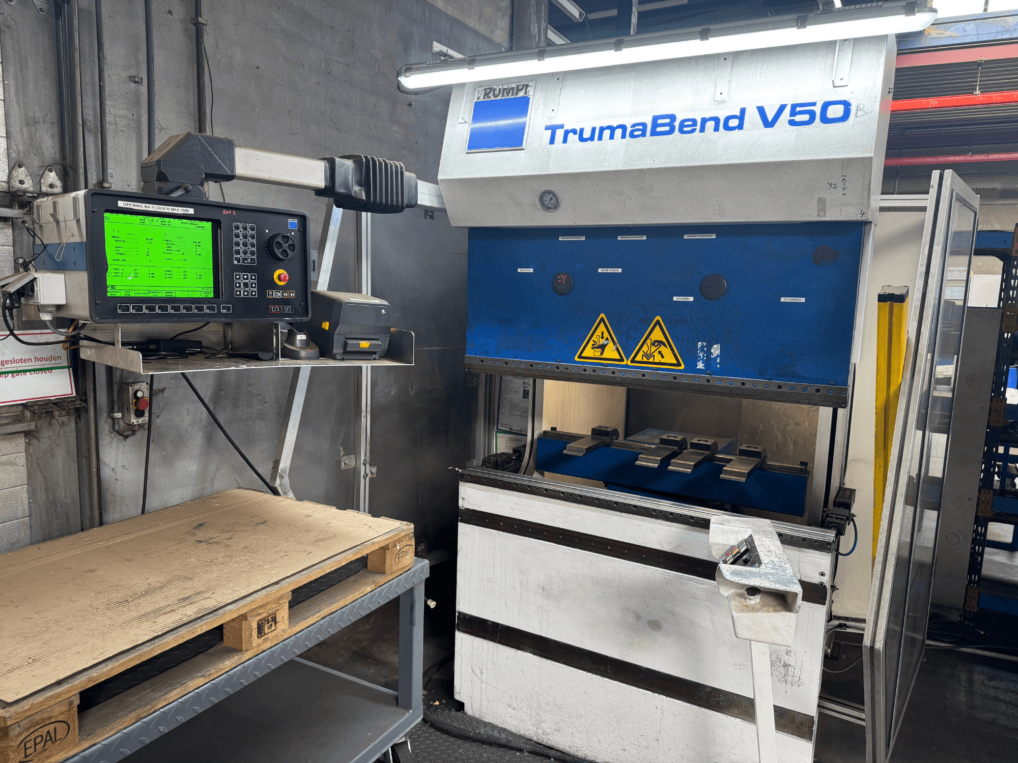 Pressa piegatrice TRUMPF TrumaBend V50, vista frontale, con pannello di controllo che visualizza le impostazioni e le avvertenze di sicurezza.