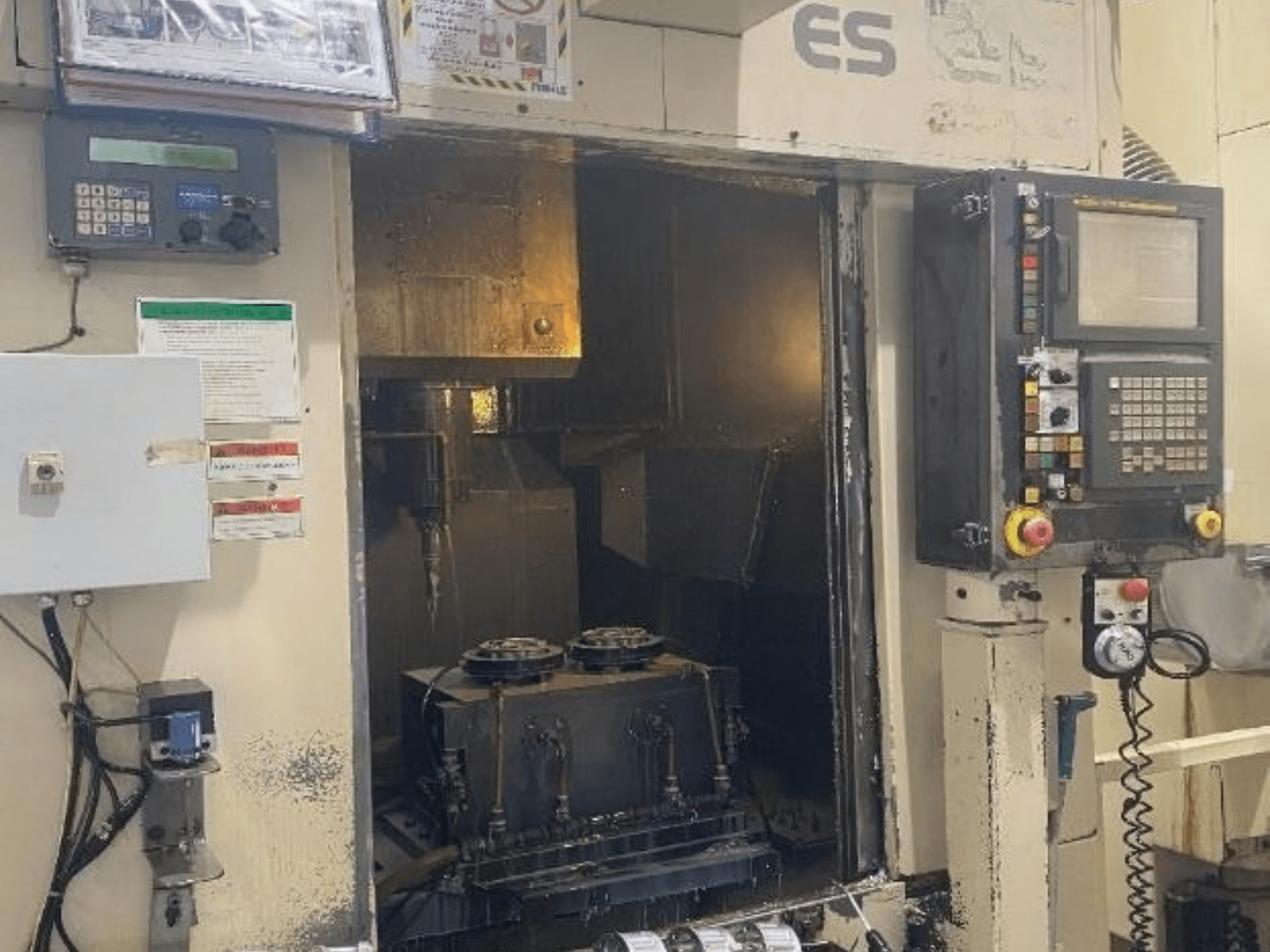Vista frontale del centro di lavorazione verticale Enshu ES450, con i comandi, la vista interna e l'area di alloggiamento degli utensili.