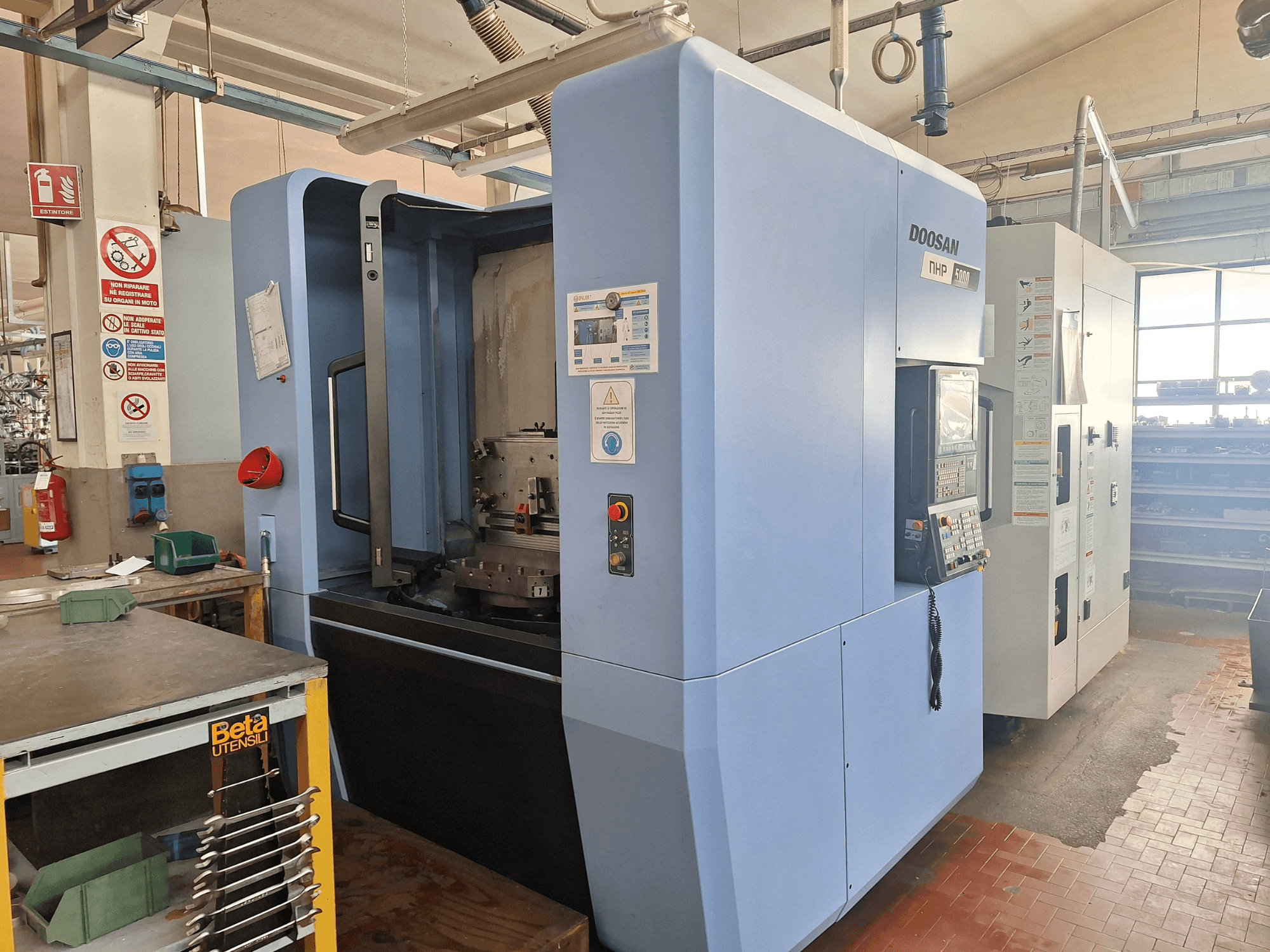 Centro di lavoro orizzontale DOOSAN NHP 5000 in un'officina, vista laterale che mostra il pannello di controllo e l'area di lavorazione.