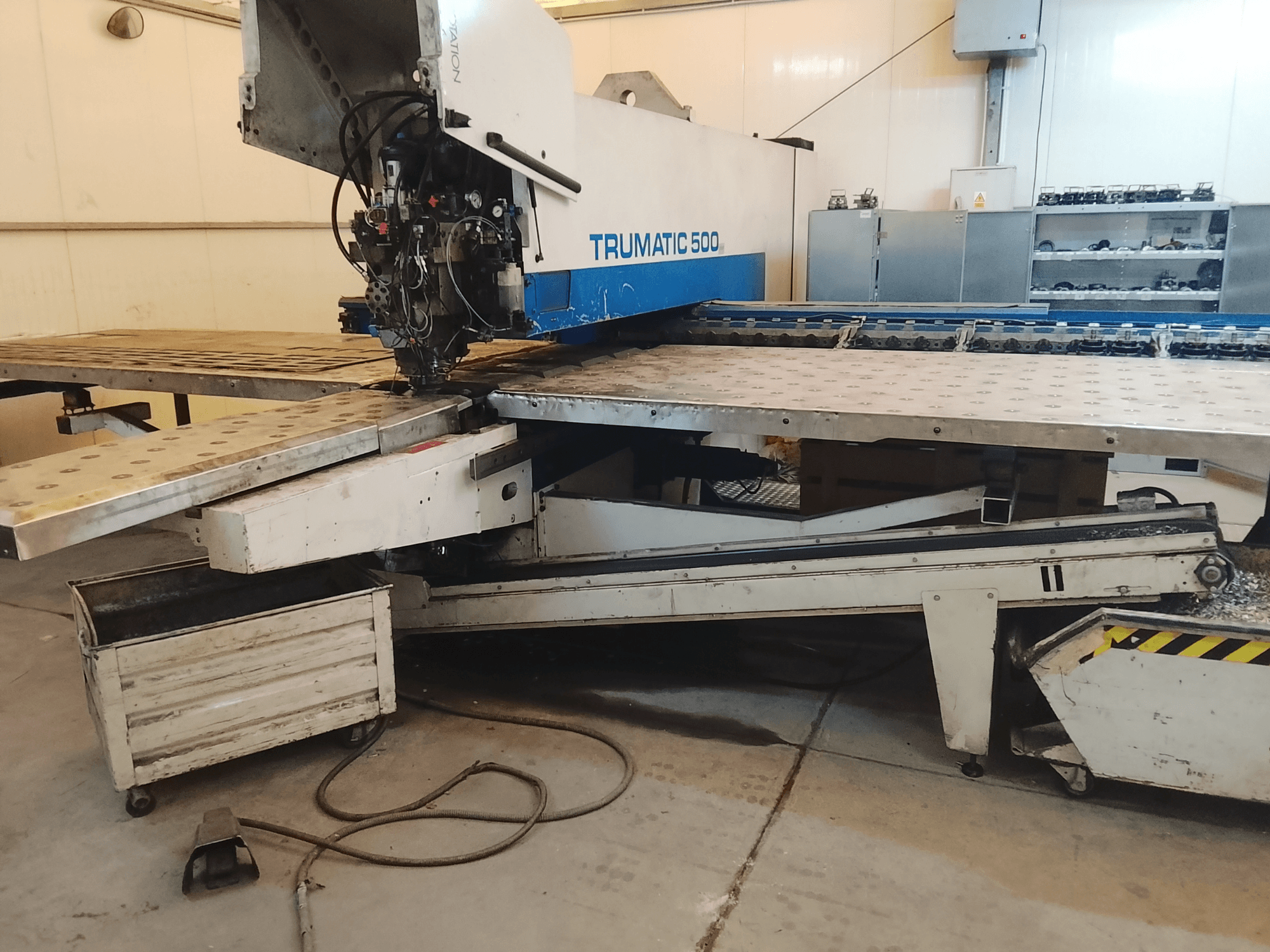 Macchina CNC TRUMATIC 500 in officina, vista laterale che mostra la testa di taglio e il piano di lavoro in metallo con fori preforati.