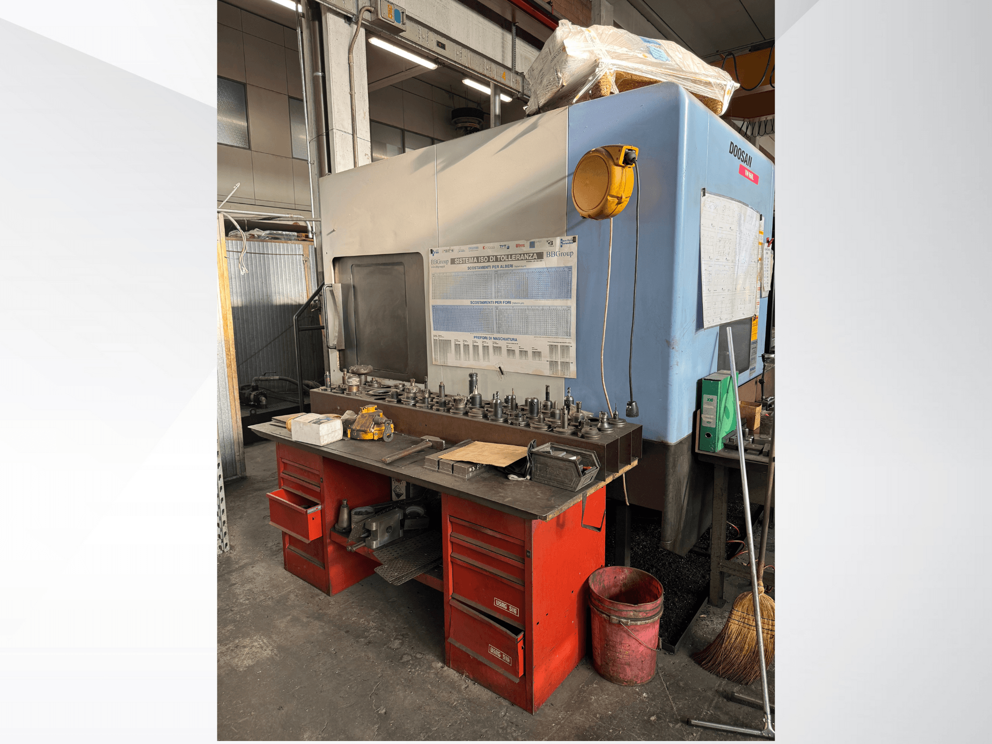 Centro di lavoro Doosan con banco di lavoro rosso e magazzino, che espone utensili e attrezzature, visto dal davanti.