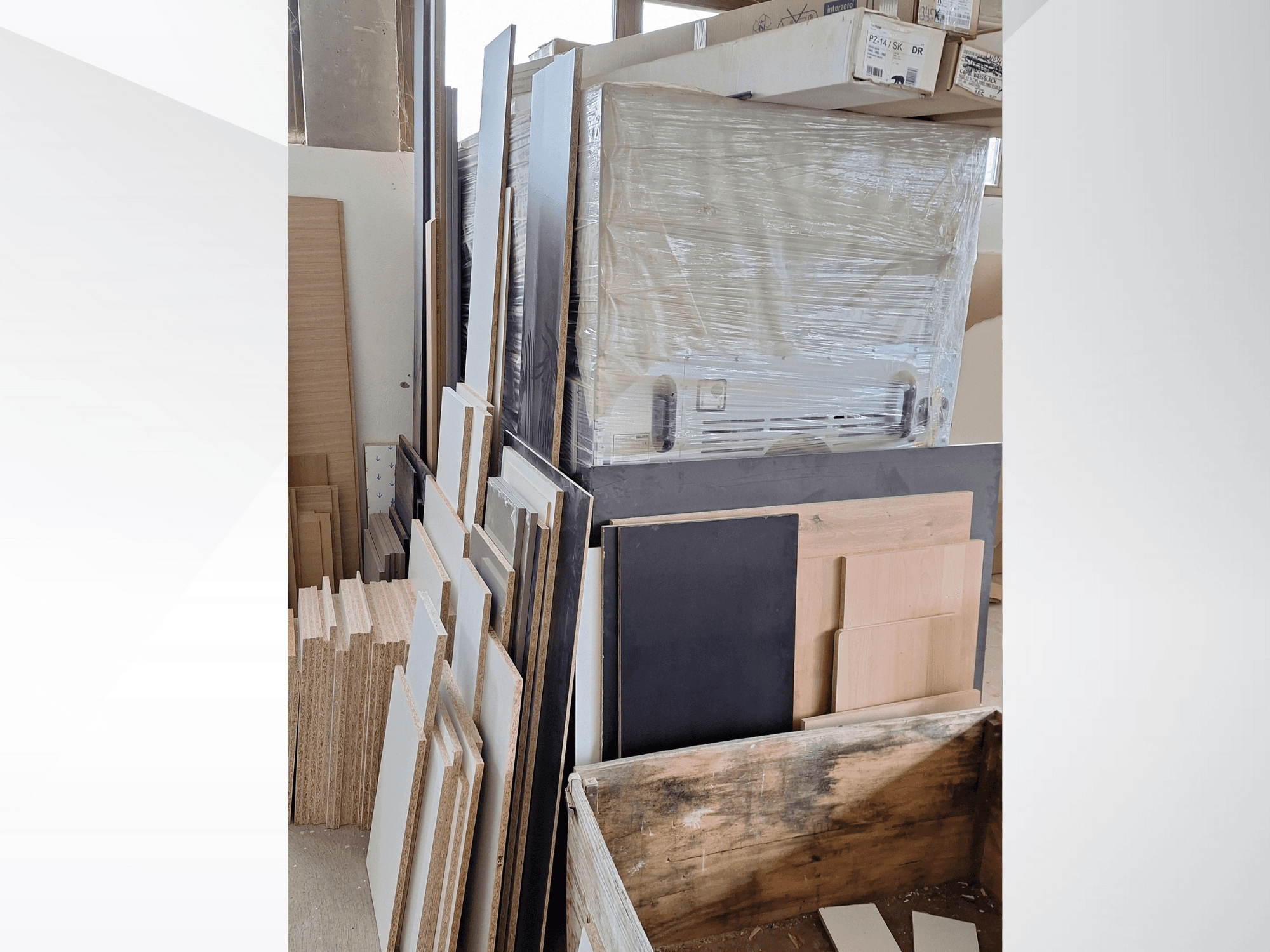 Pannelli e tavole di compensato assortiti impilati, con varie finiture; vista frontale dei materiali in un ambiente di laboratorio.