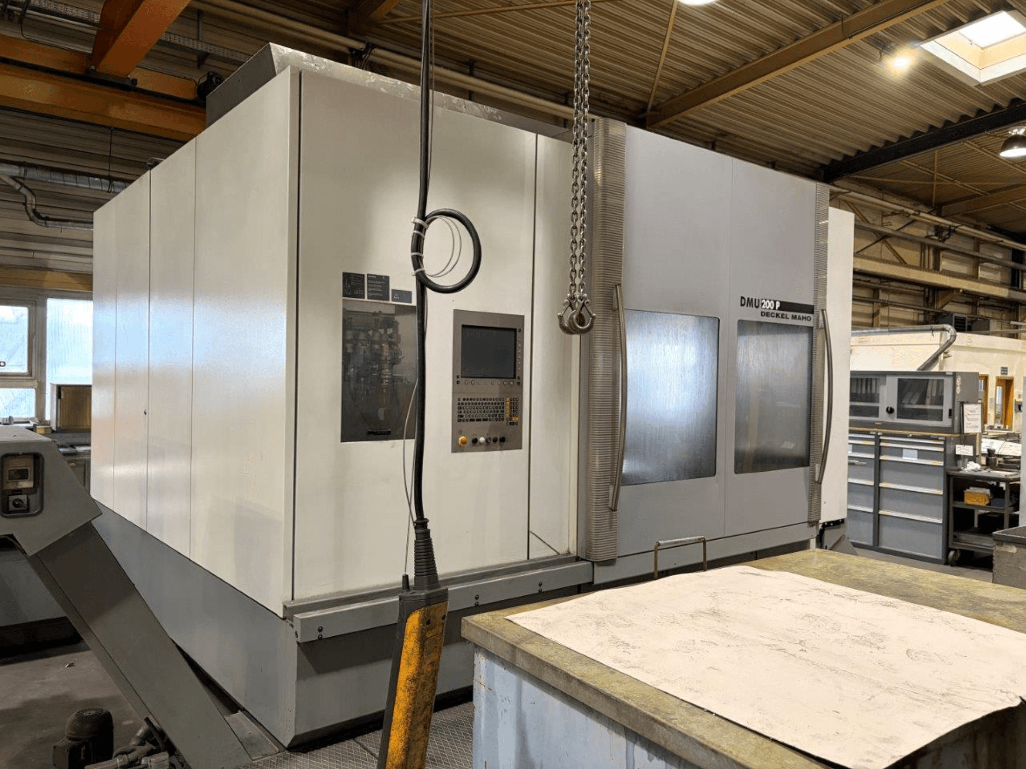 Centro di lavoro universale DMG MORI DMU 200 in un'officina, vista frontale, che mostra il pannello di controllo e le caratteristiche esterne.