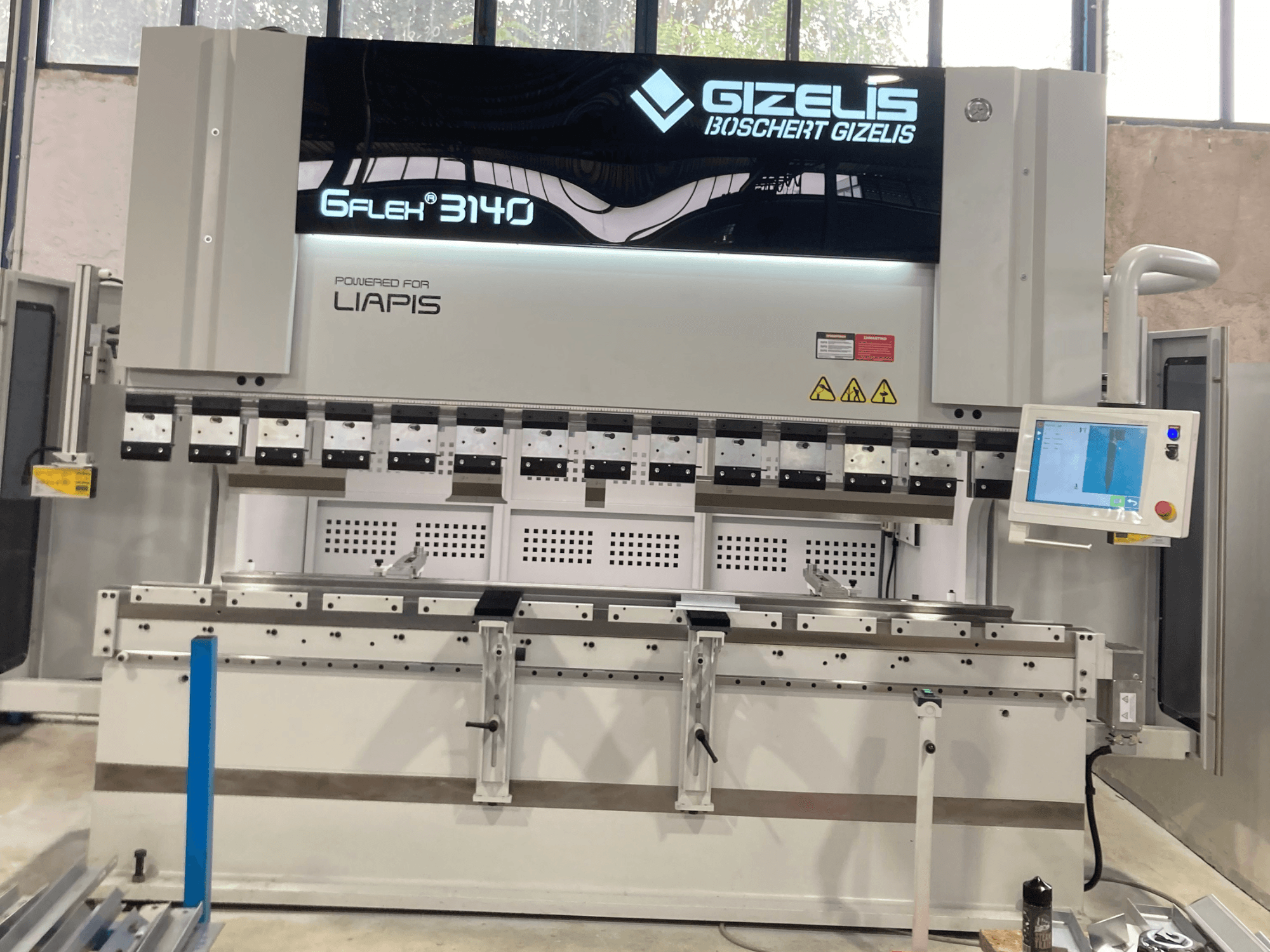 Pressa idraulica GIZELIS G-FLEX 3140 in vista frontale con schermo di controllo, dotata di più strumenti di piegatura ed etichette di sicurezza.