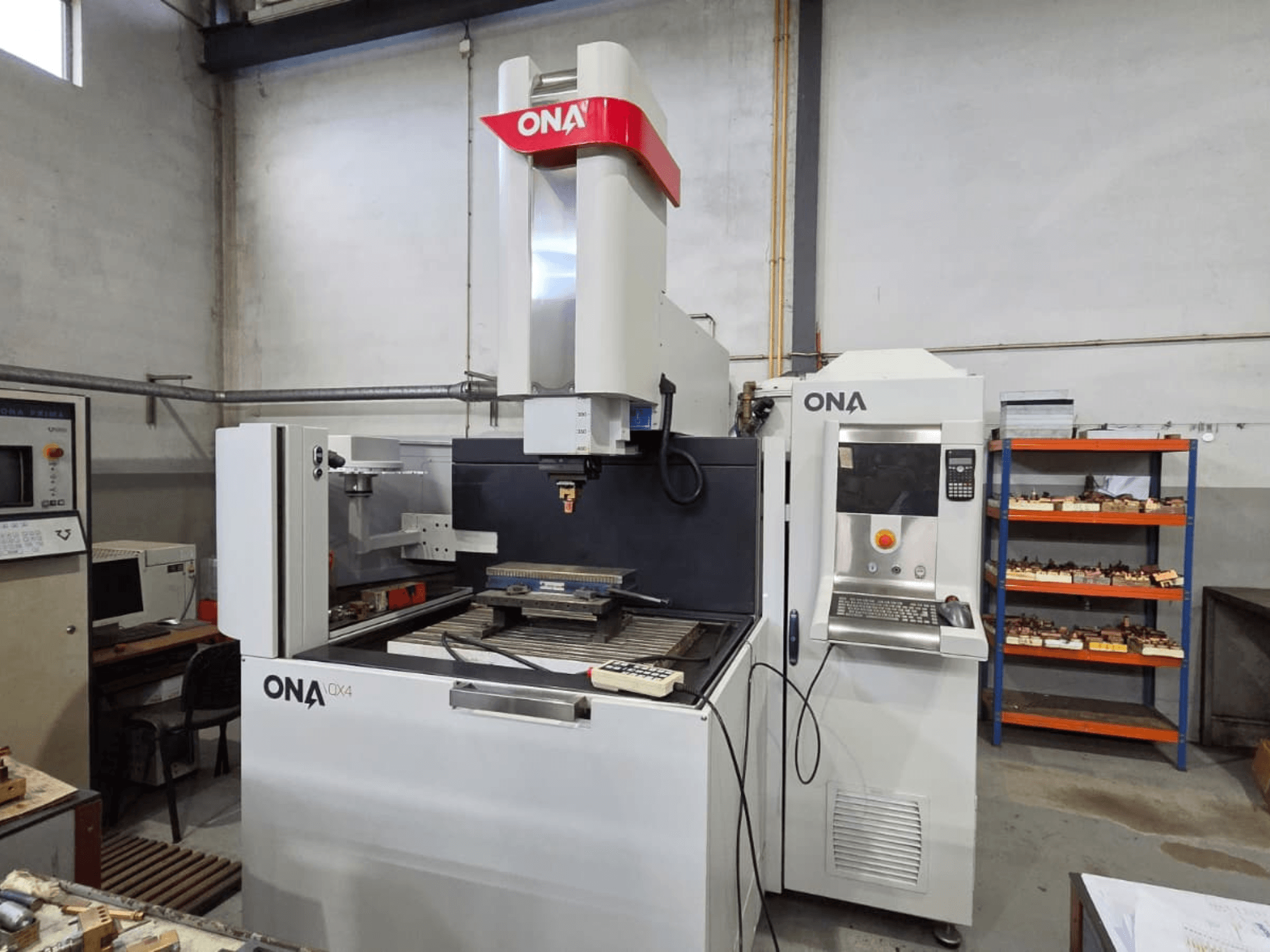 Macchina per elettroerosione a tuffo ONA QX4 in vista laterale, con pannello di controllo e tavolo di lavoro, situata in un'officina.
