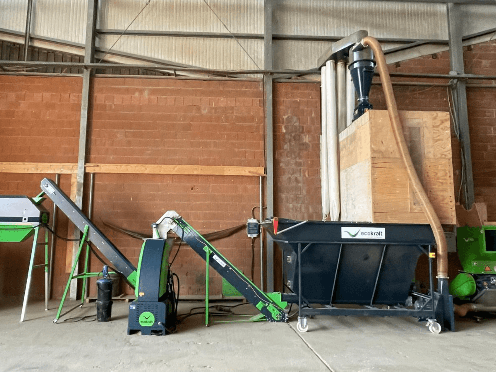Macchina utensile ECOKRAFT LP 22 in un magazzino, dotata di un nastro trasportatore e di un sistema di aspirazione delle polveri. Vista laterale che mette in evidenza i componenti funzionali.