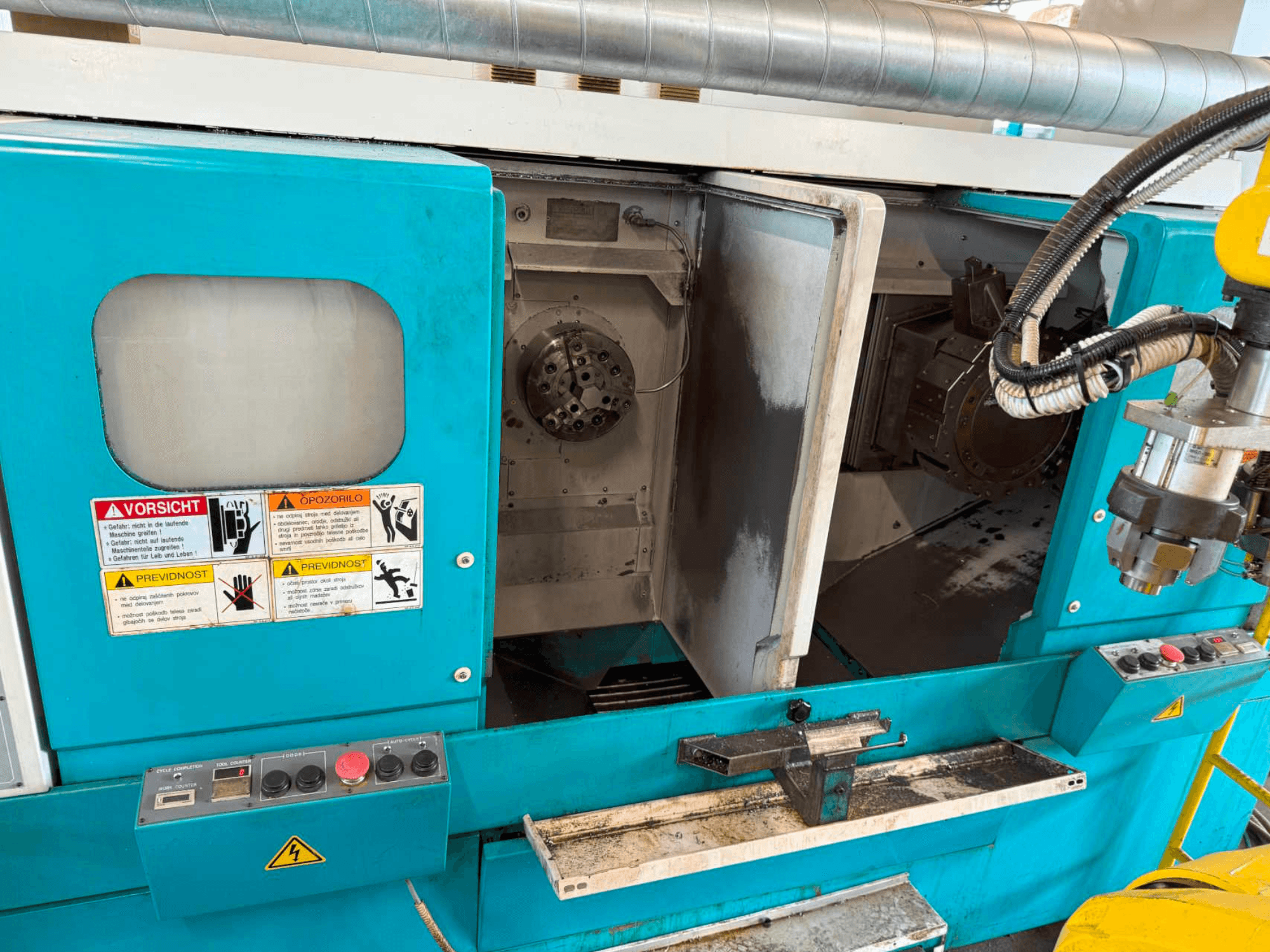 Tornio orizzontale DOOSAN H310T, vista frontale che mostra il pannello di controllo e l'area del mandrino con le avvertenze di sicurezza.