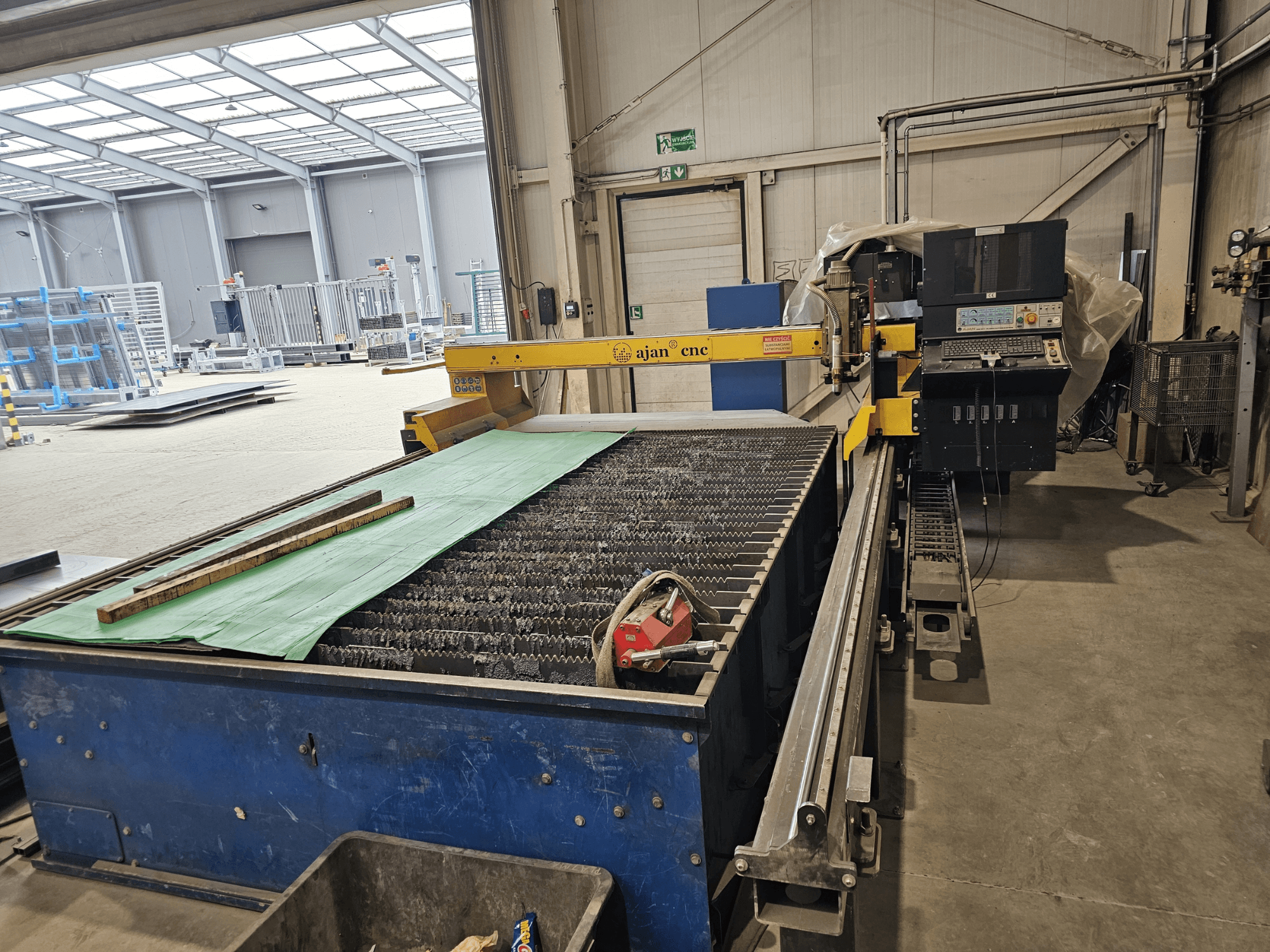 AJAN PP16011 Macchina per il taglio al plasma automatico in vista laterale, con tavolo di taglio e pannello di controllo, in un ambiente di officina.