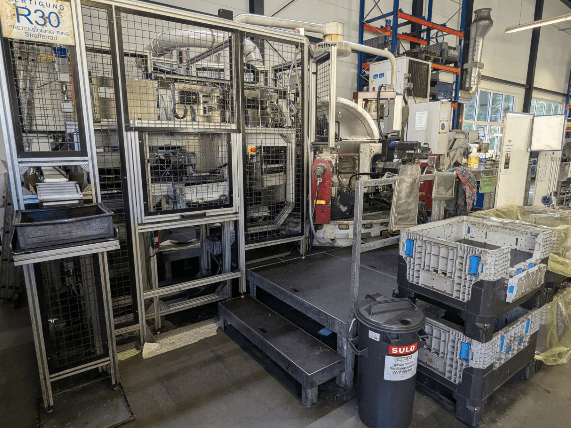 Macchina utensile PFIFFNER HB 32/16 in un'officina, vista frontale che mostra l'area di produzione con contenitori e recinzione di sicurezza.